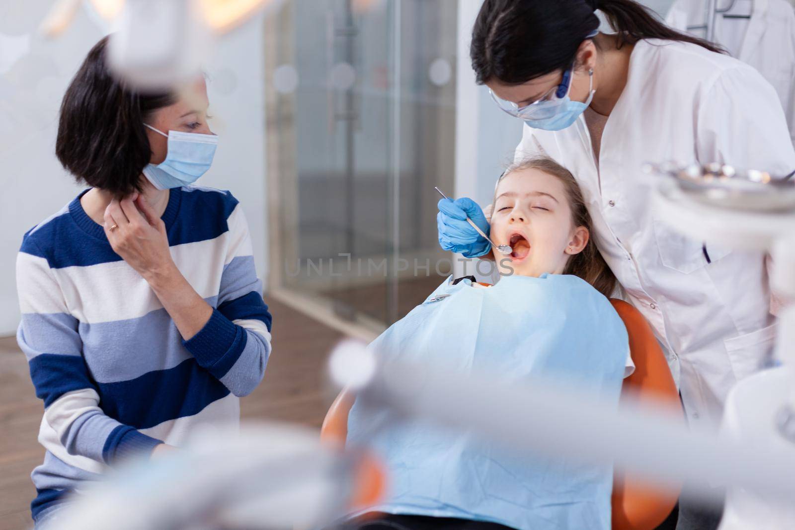 Family visit at dentist office for dental and oral hygine. Dentistry specialist during child cavity consultation in stomatology office using modern technology.