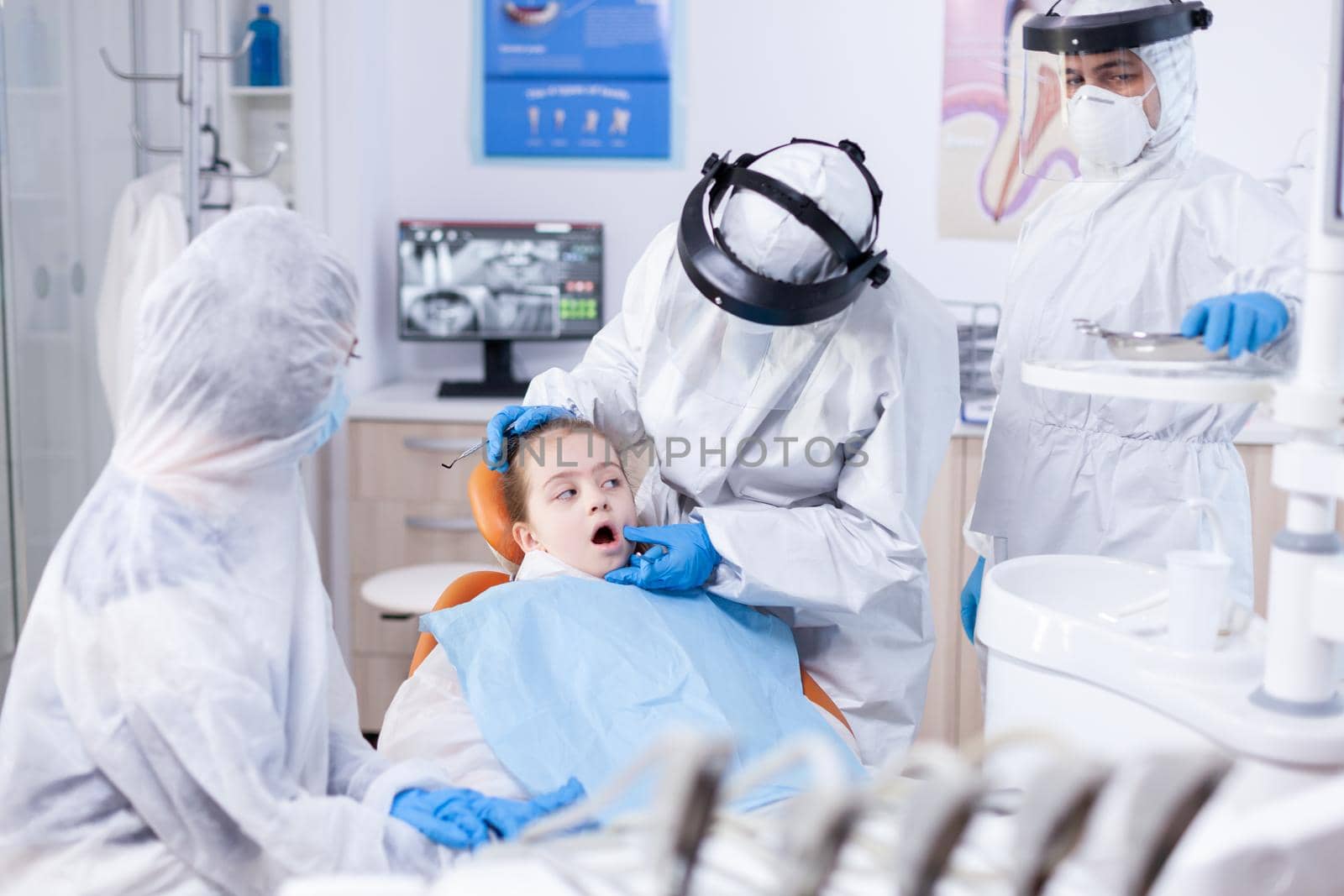 Little girl with mouth open sitting on dental chair by DCStudio
