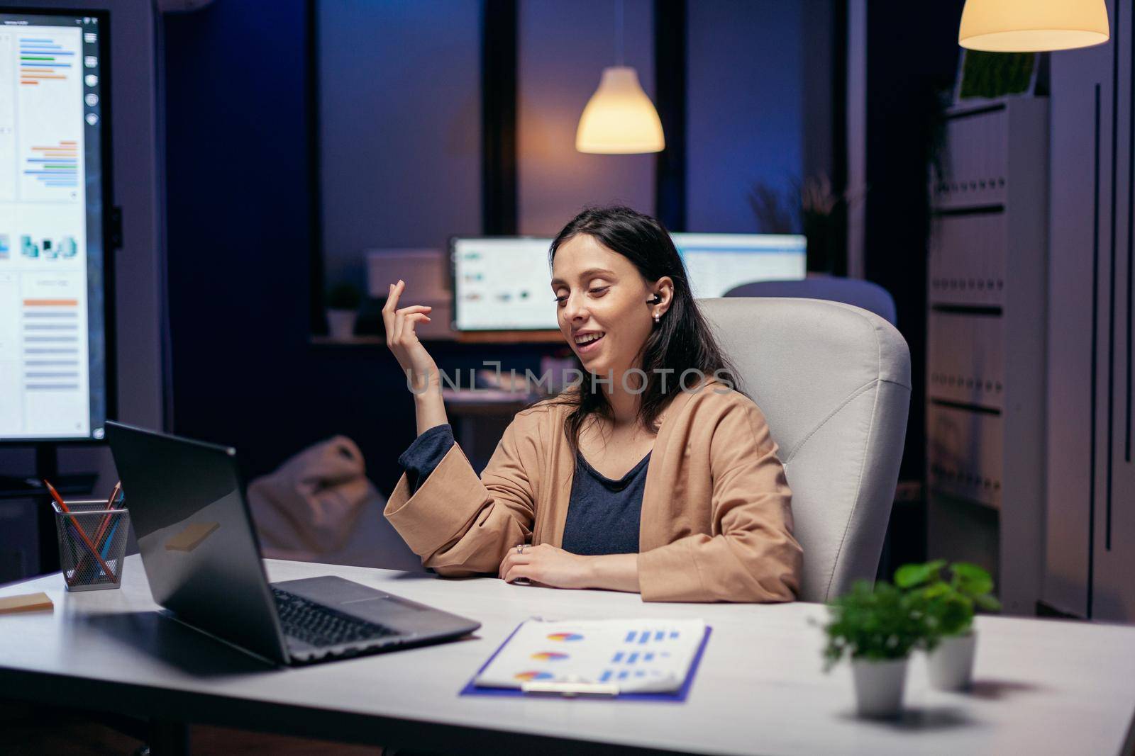 Employee having video conference working overtime in business workplace. Woman working on finance during a video conference with coworkers at night hours in the office.