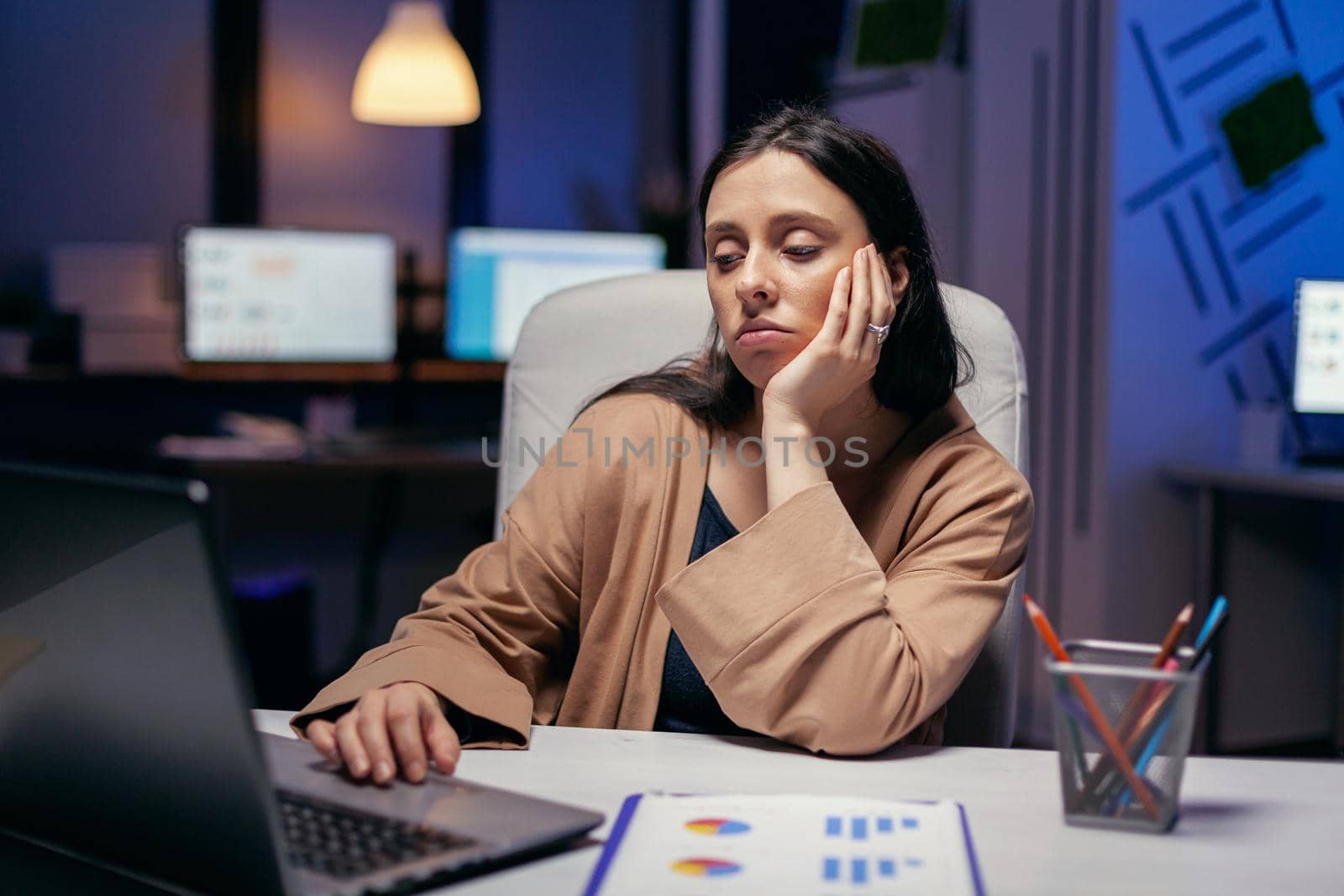 Exhausted businesswoman looking at computer by DCStudio