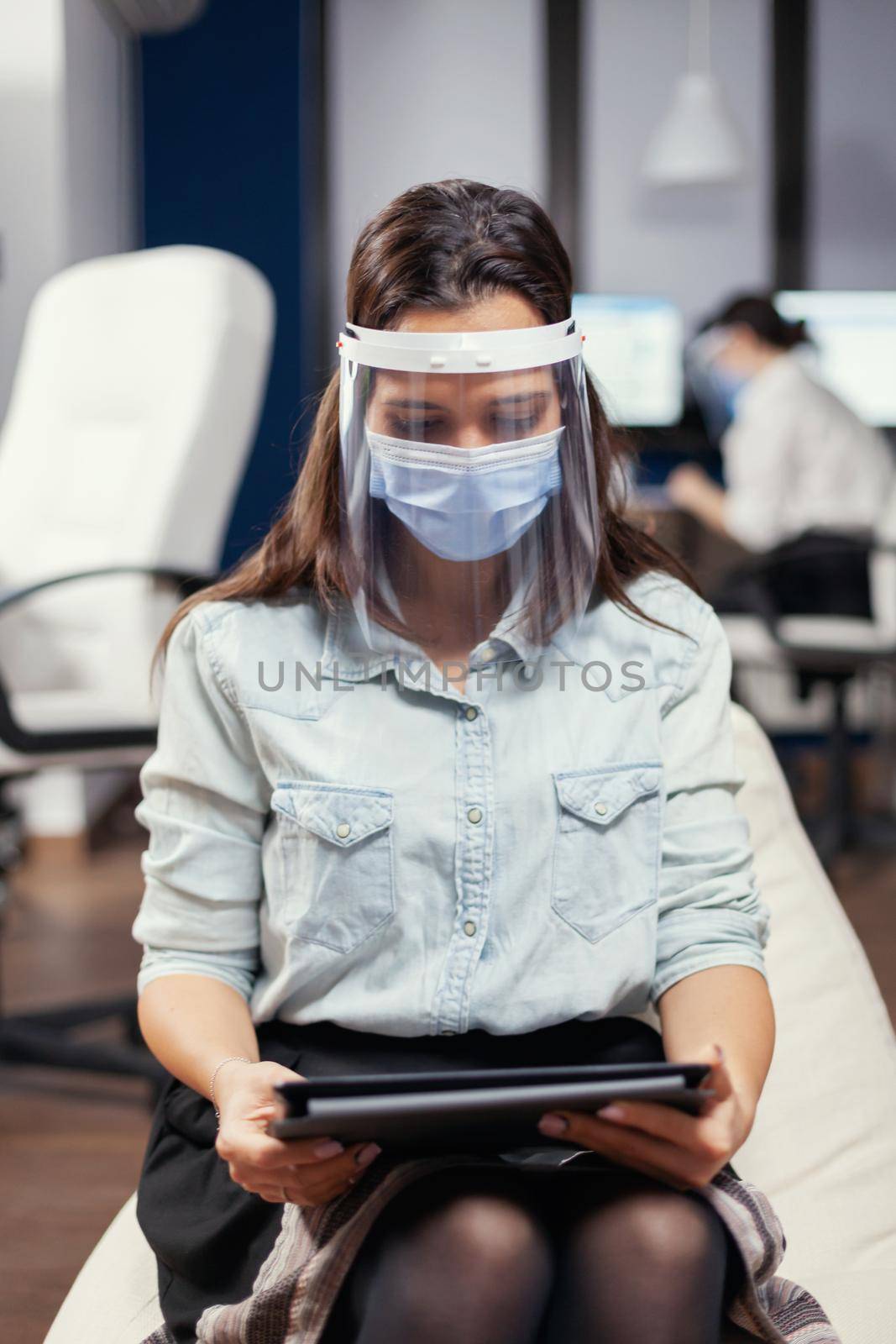 Woman entrepreneur wearing face mask against covid19 as safety precaution. Multiethnic business team working respecting social distance during global pandemic with covid-19.