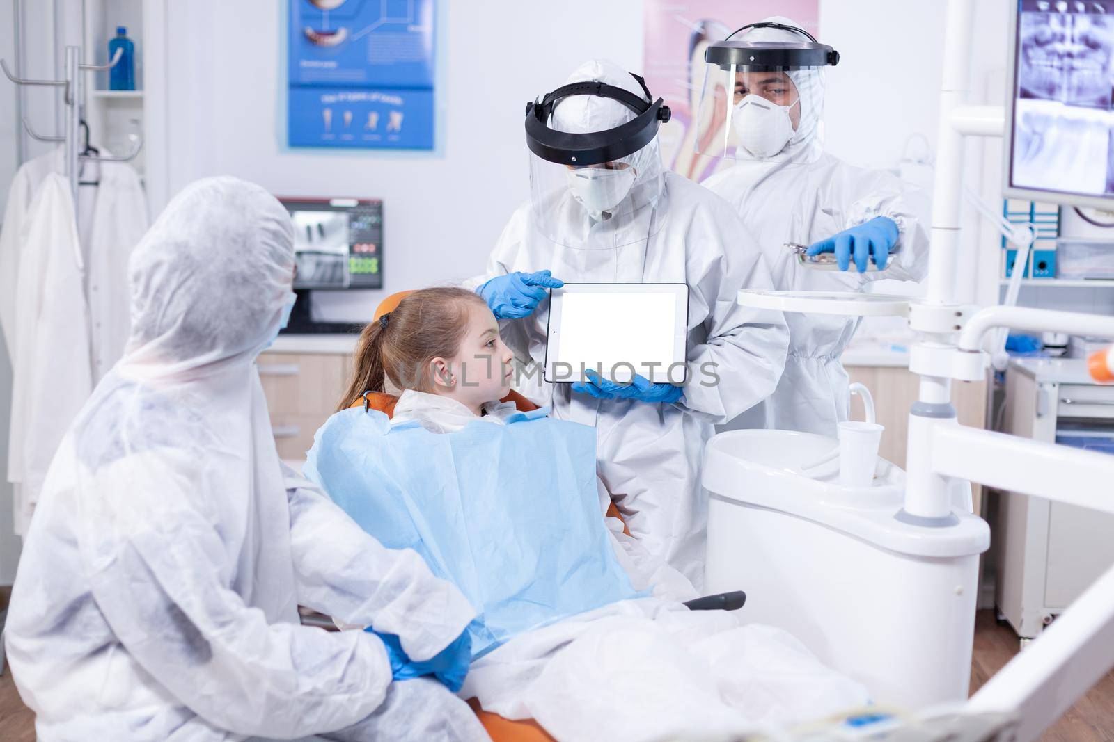 Dentist dressed in ppe suit using digital device by DCStudio