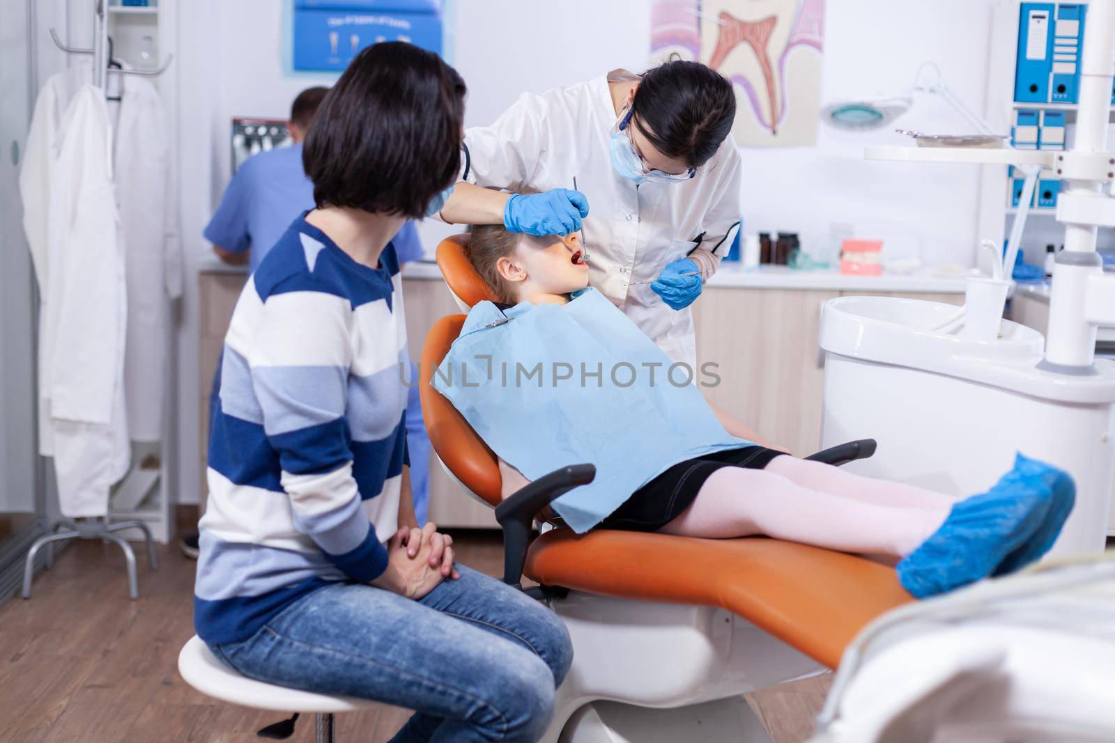 Dentist in the course oral treatment for little kid with caries. Dentistry specialist during child cavity consultation in stomatology office using modern technology.