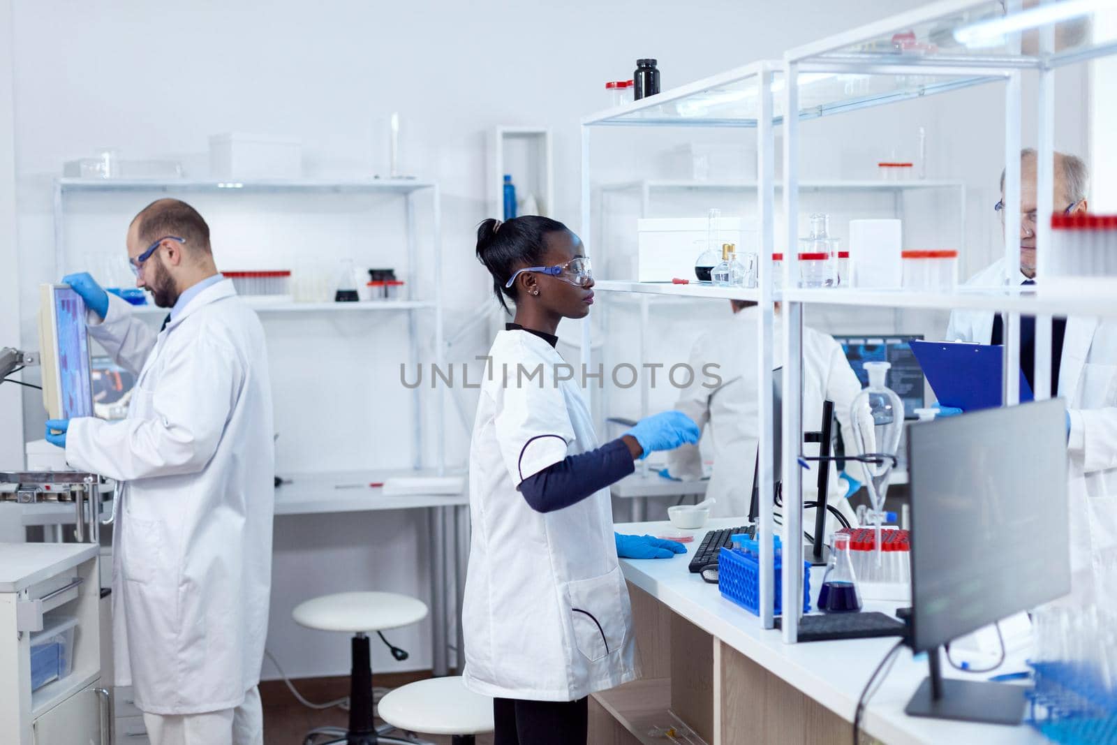 African scientist using glass flask in sterile microbiology laboratory by DCStudio
