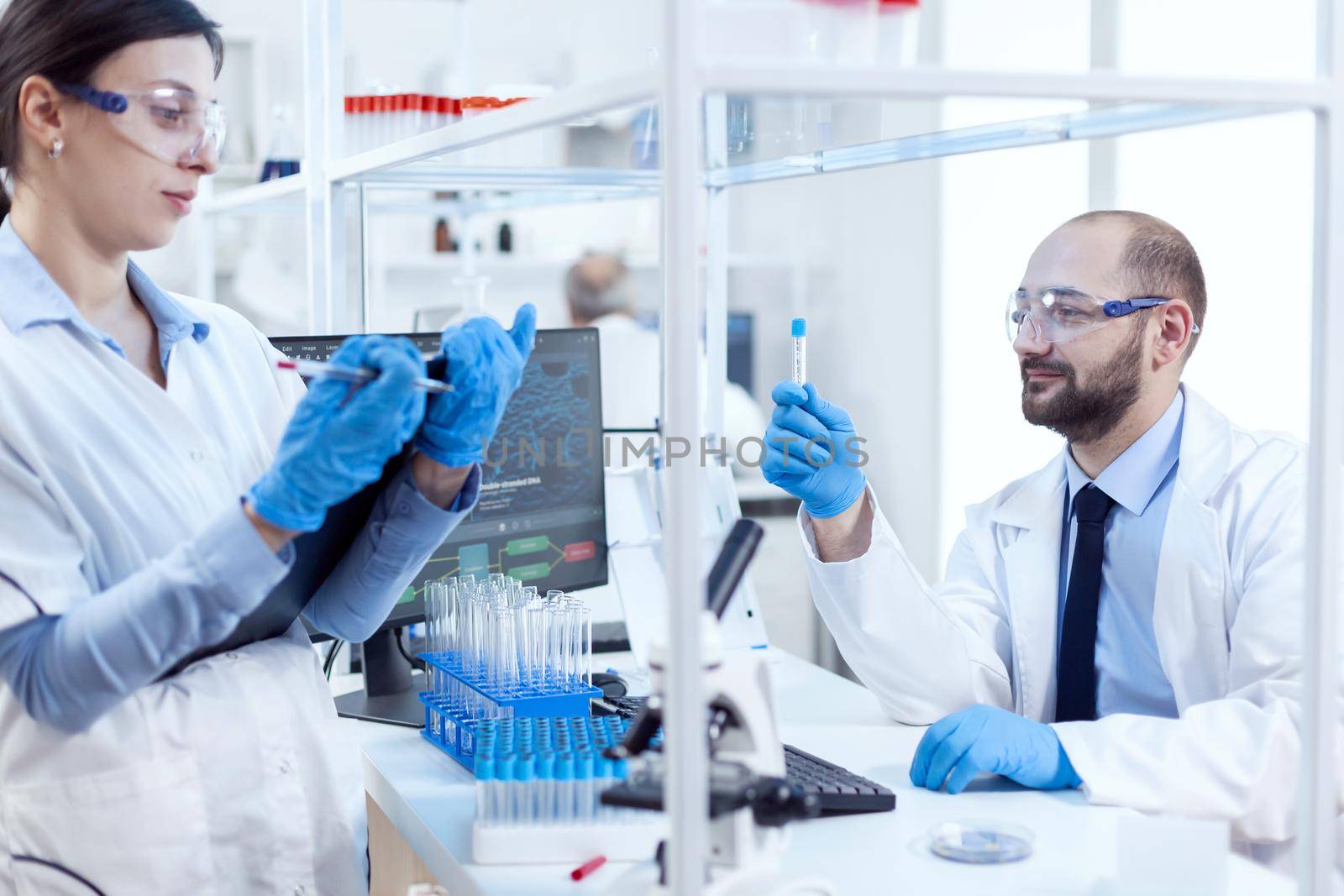 Pharmacology scientist engineering genetic material in busy science lab. Team of chemical chemists working together in sterile microbiology lab doing research.