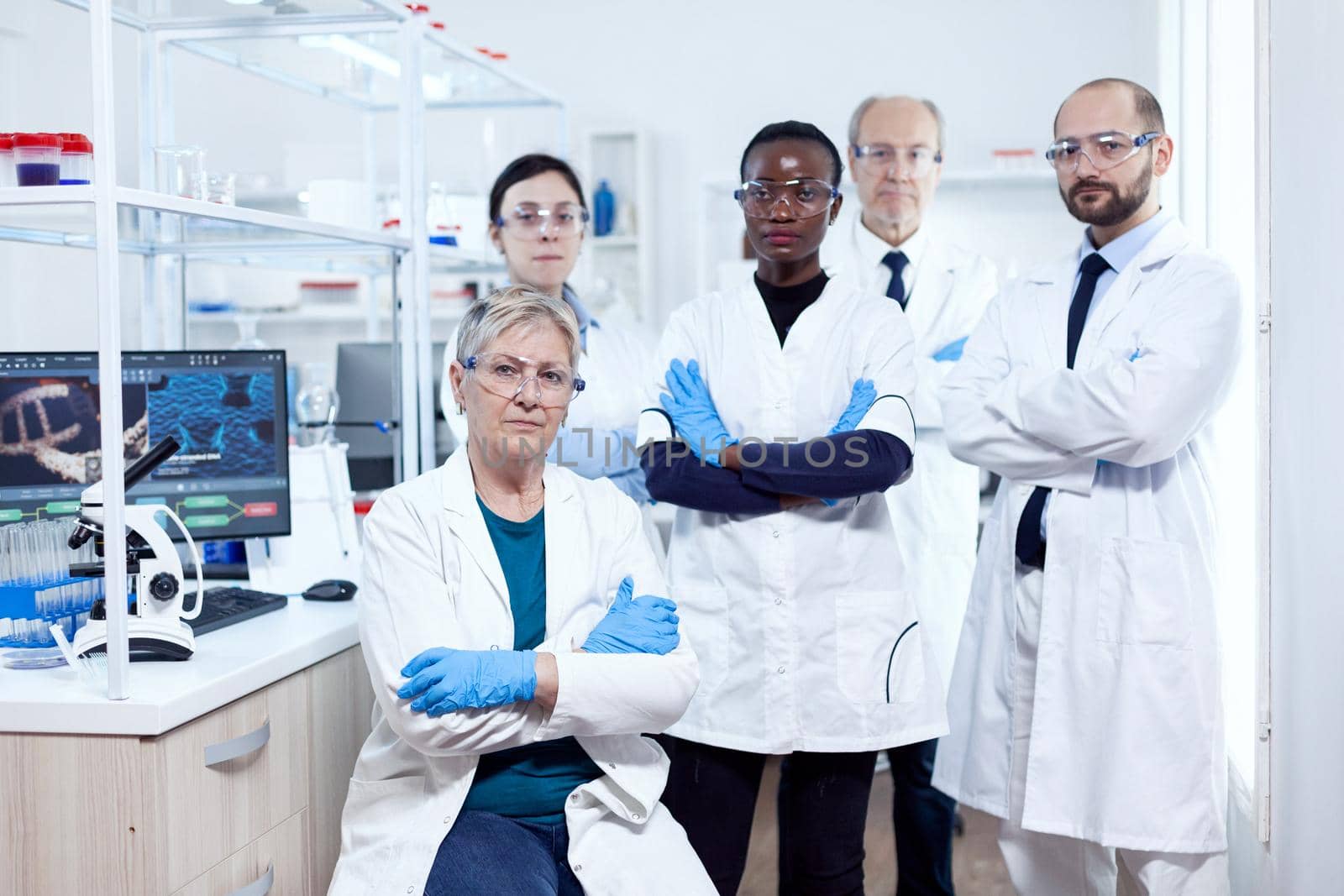 Healthcare researcher at workplace standing together with arms crossed. African healthcare scientist in biochemistry laboratory wearing sterile equipment.