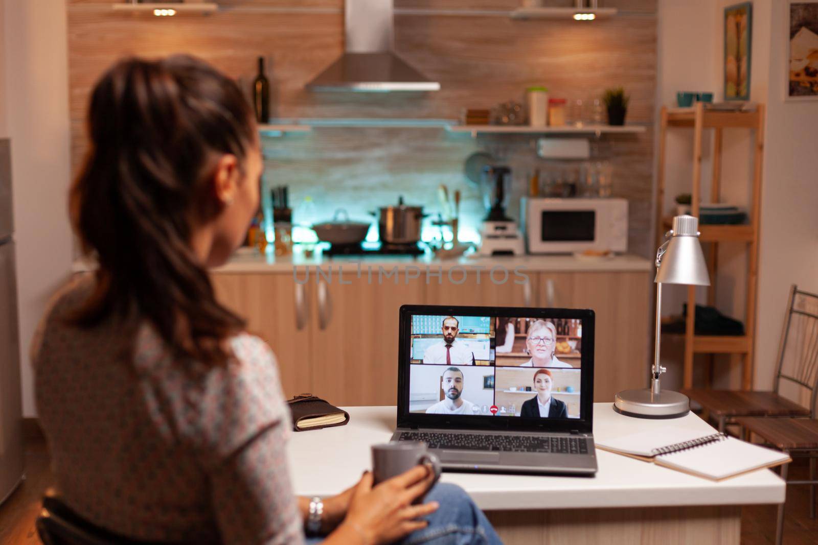 Businesswoman having a video conference with team during midnight using laptop in home kitchen. Corporate meeting using modern technology, laptop late at night , tech, agency, advisor, work, discussion.