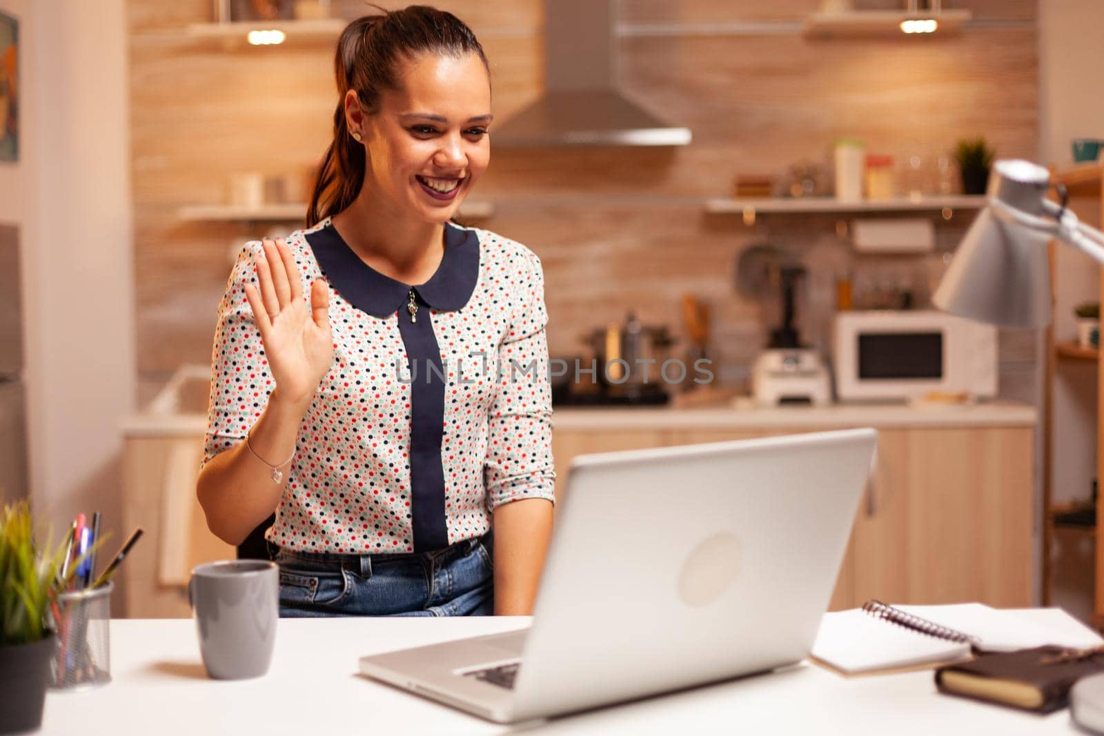 Cheerful woman waving during a video call by DCStudio