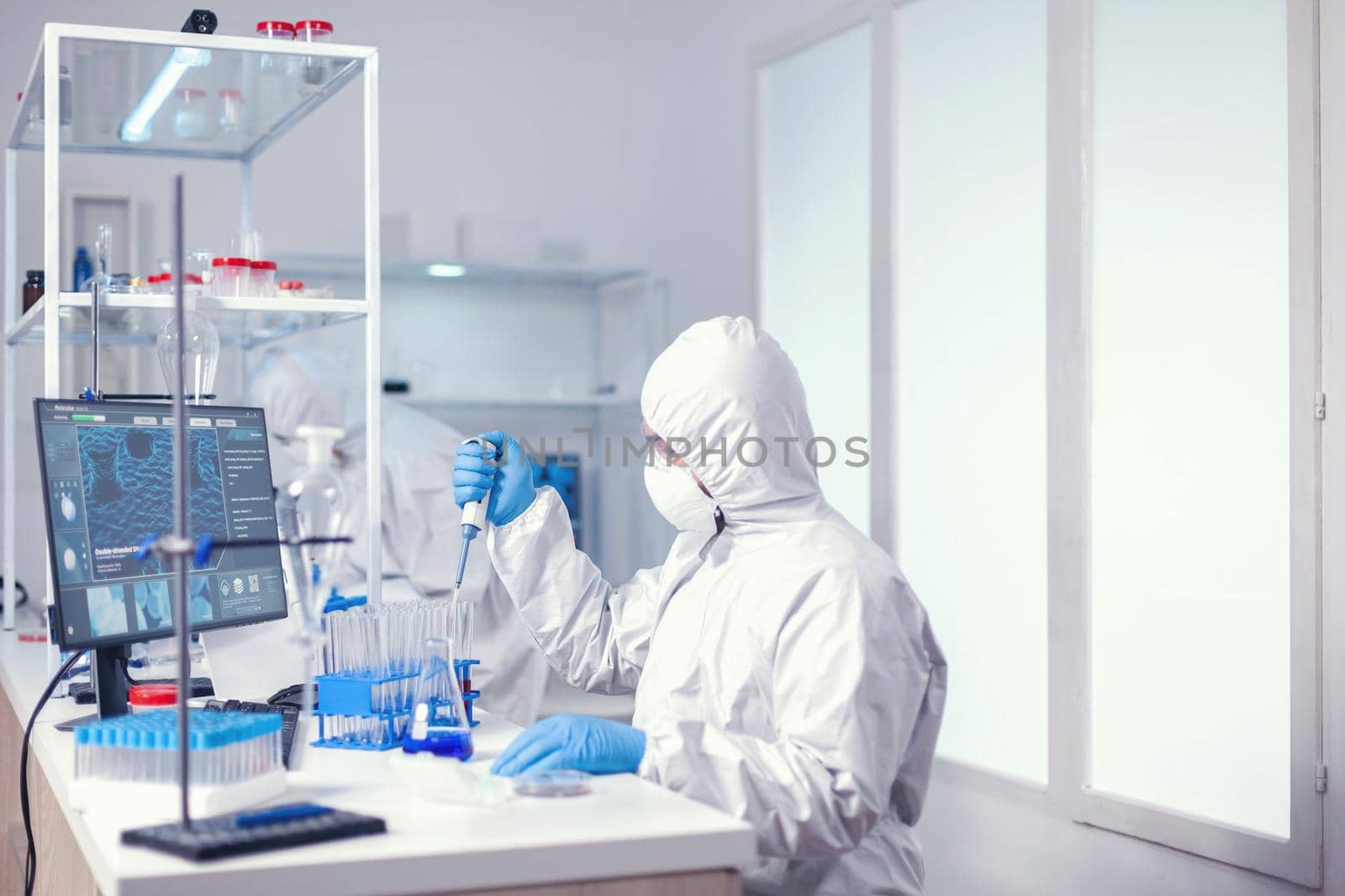 Doctor taking carefully sample from test tube using automatic pipette Chemist in modern laboratory doing research using dispenser during global epidemic with covid-19.