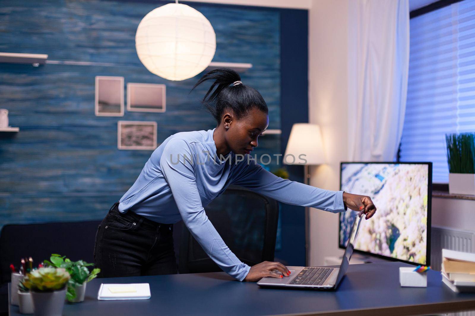 African entrepreneur working from home late at night using laptop to workin on important project. Black entrepreneur sitting in personal workplace writing on keyboard.