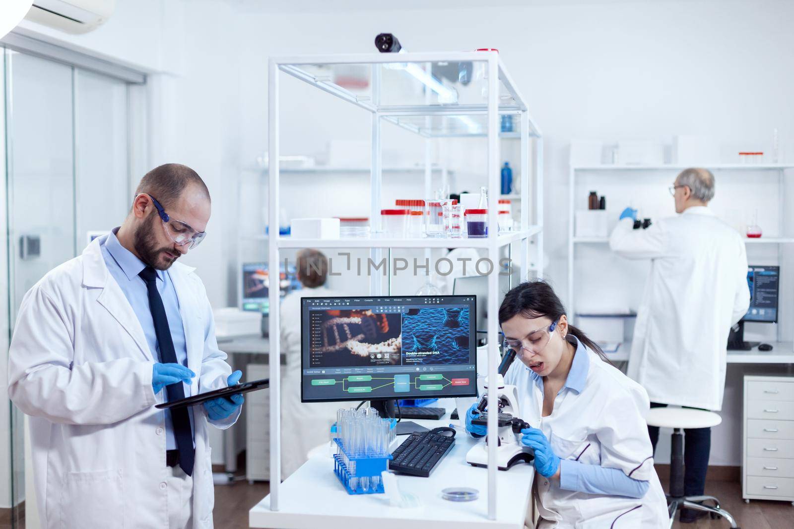 Group of scientist doing health study using microscope and tablet pc by DCStudio