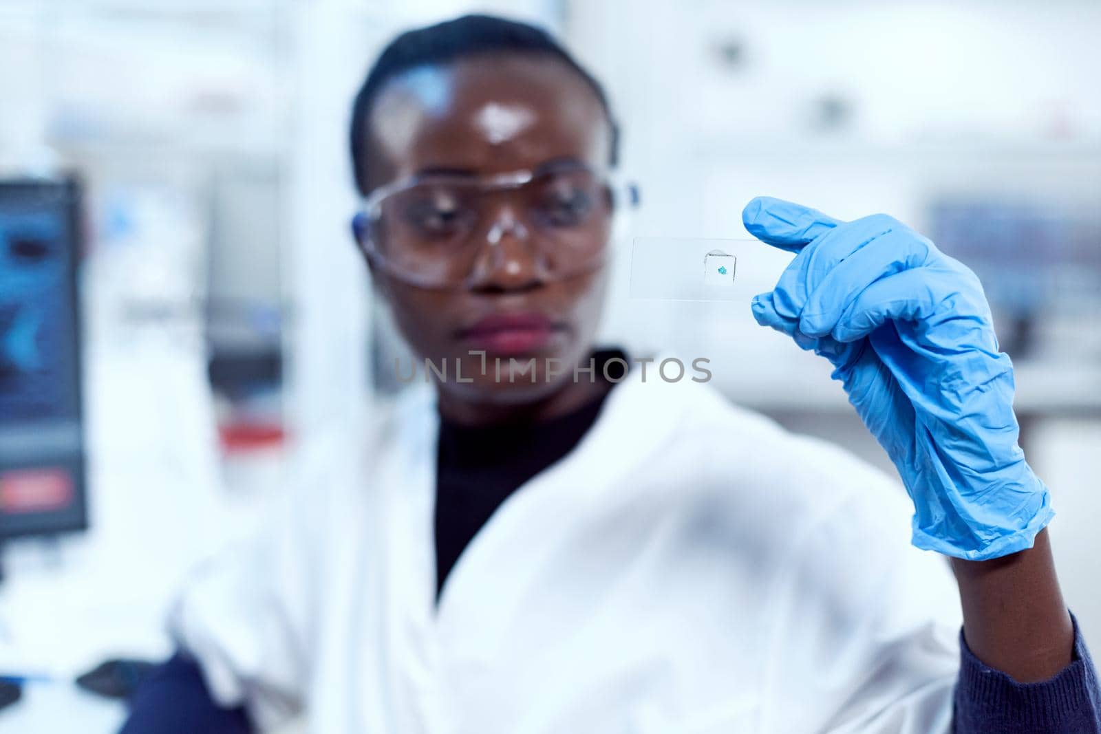 Multiethnic researcher during study holding microscope sample by DCStudio