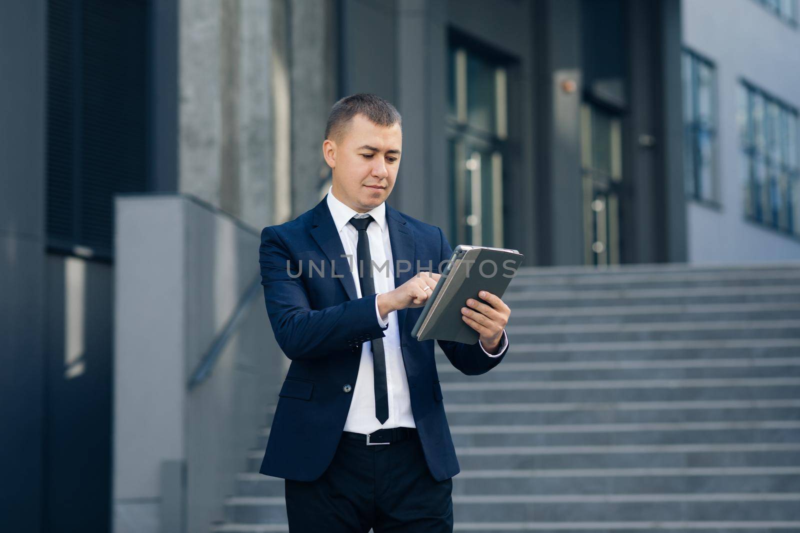 Businessman Working On Tablet Computer Outside Office. Cool businessman using electronic tablet