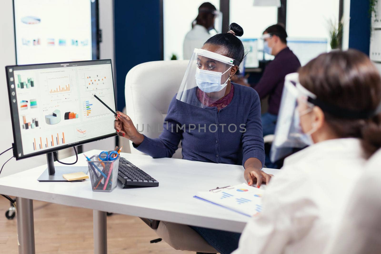 African businesswoman analysing colorful graph at office by DCStudio