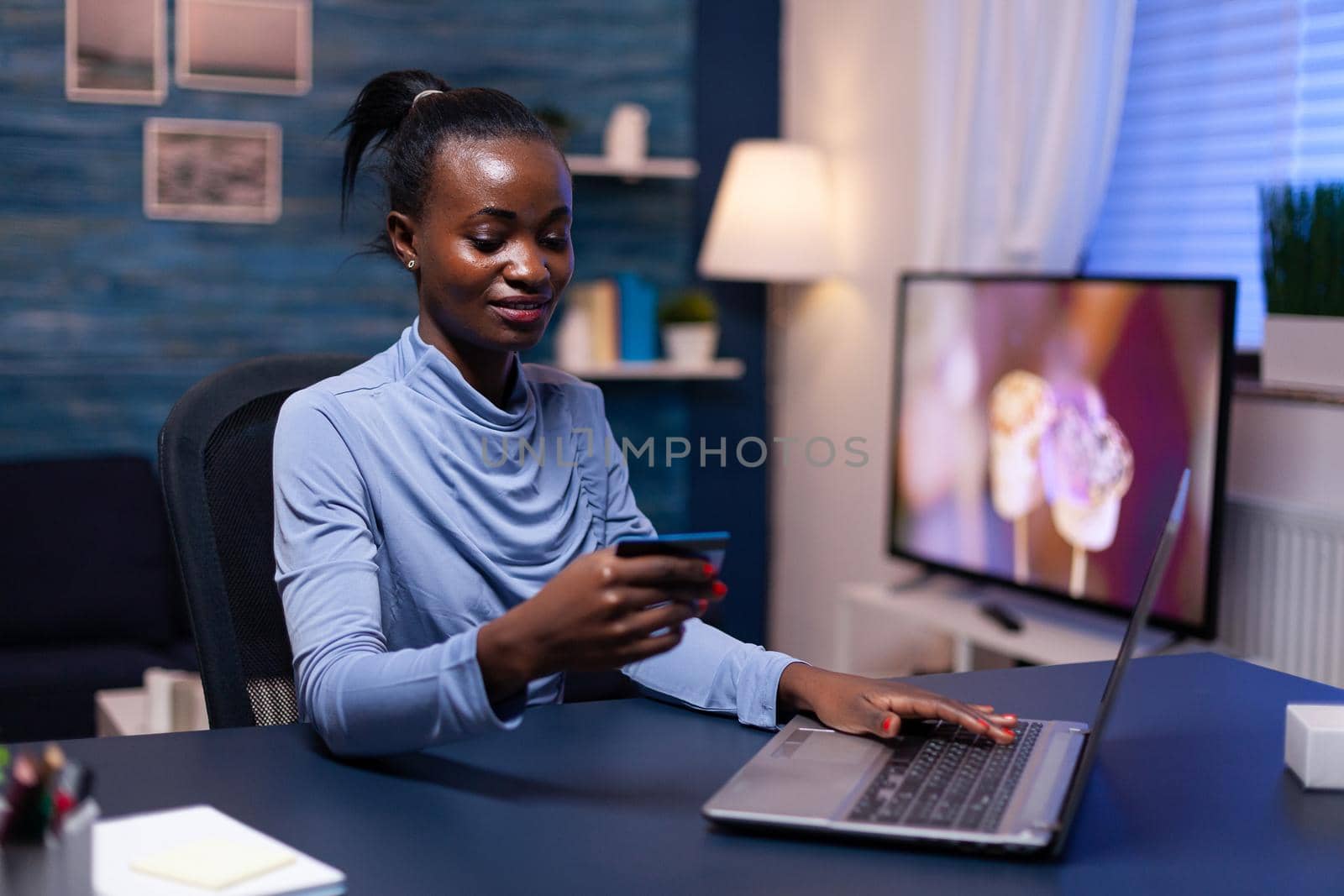 African woman looking at cw security code typing data on webstite for web store. Employee making paymant transaction from home on digital notebook.