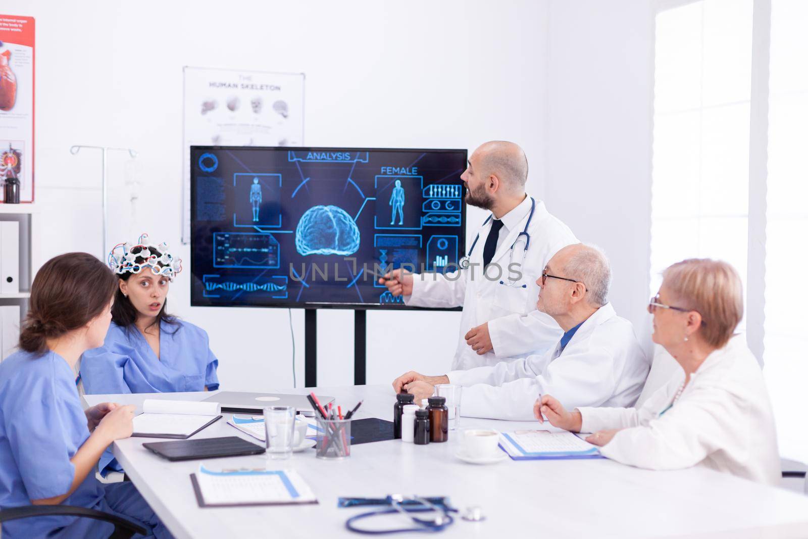 Medical nurse doing eeg scan during neuoroscience experiment and diagnosis. Monitor shows modern brain study while team of scientist adjusts the device.