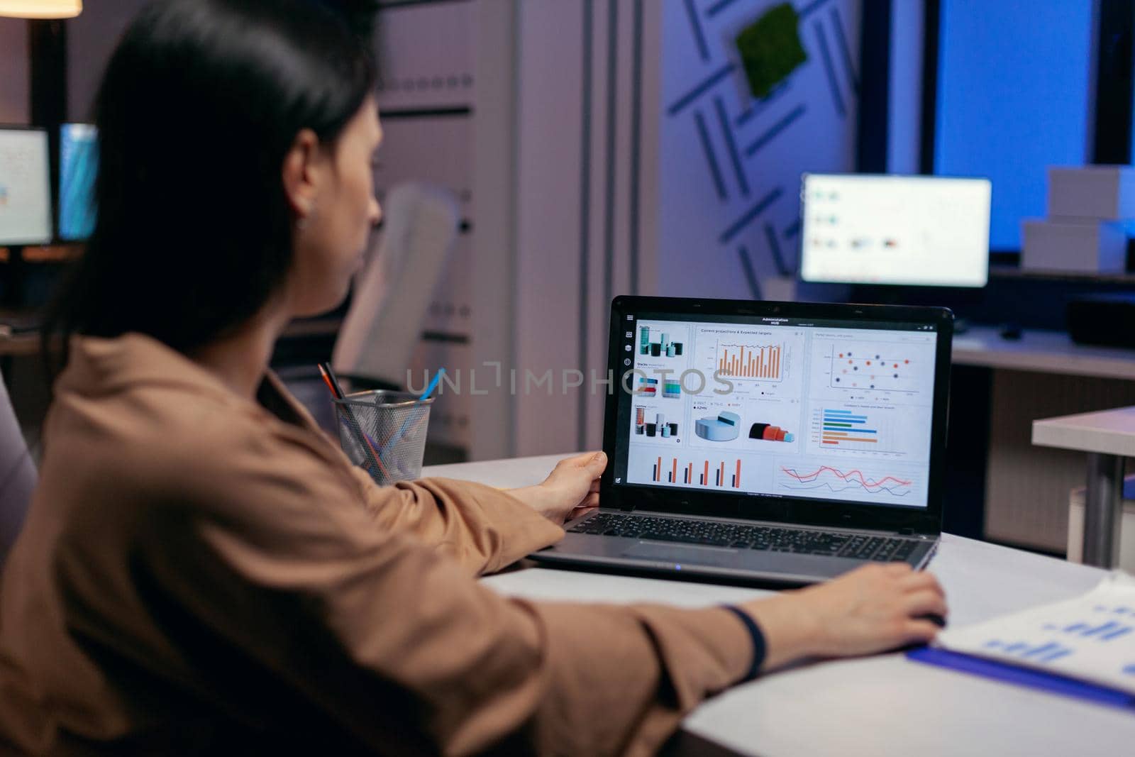 Busy business woman working on financial reports checking statistics graphs, looking at laptop in the course of deadline. Businesswoman looking at statistics on laptpop screen sitting at her workplace doing overtime.