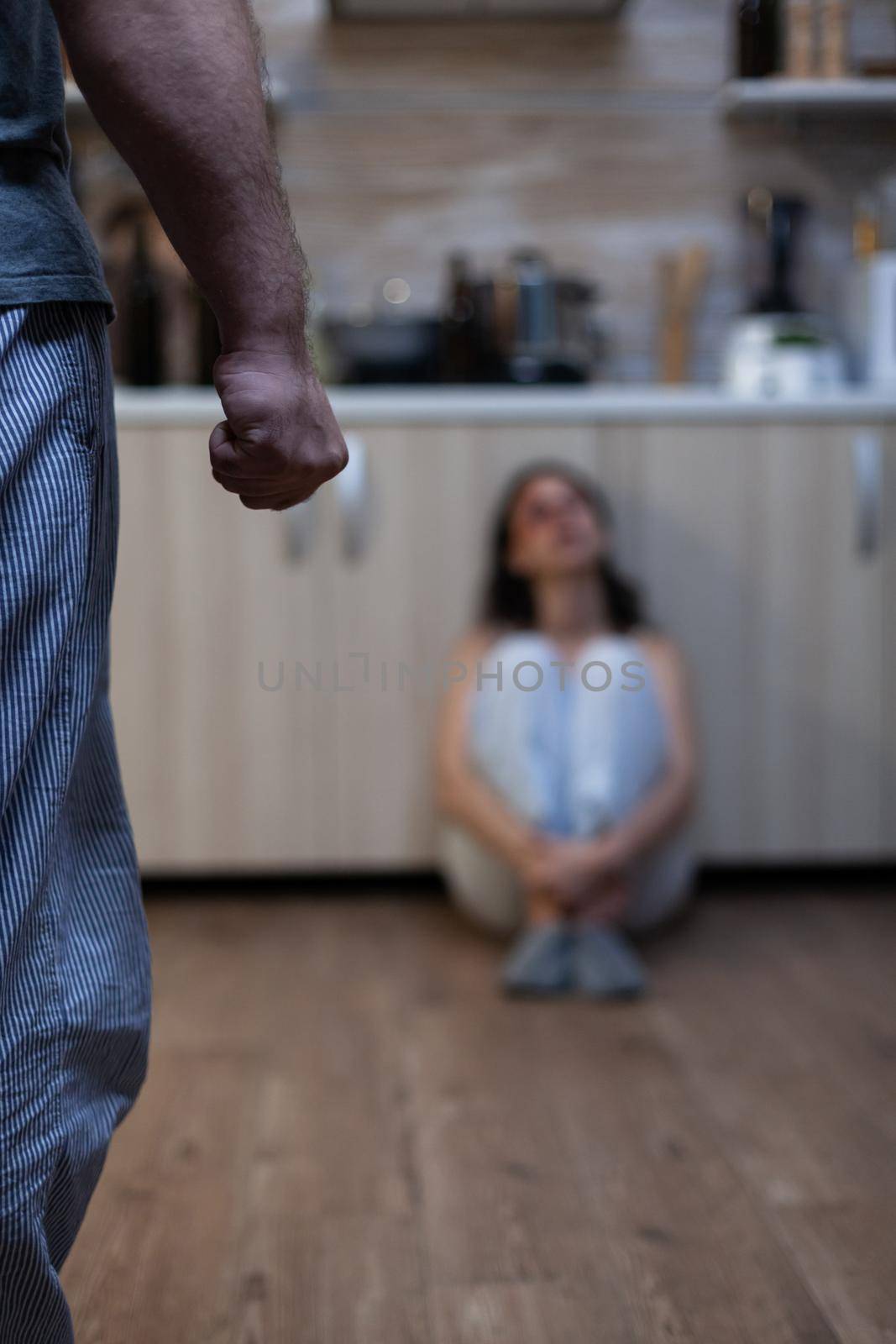 Close up of clenched fist of aggressive man after abusing woman, during domestic violence and physical trauma. Violent husband threatening helpless hurt wife with bruises on face