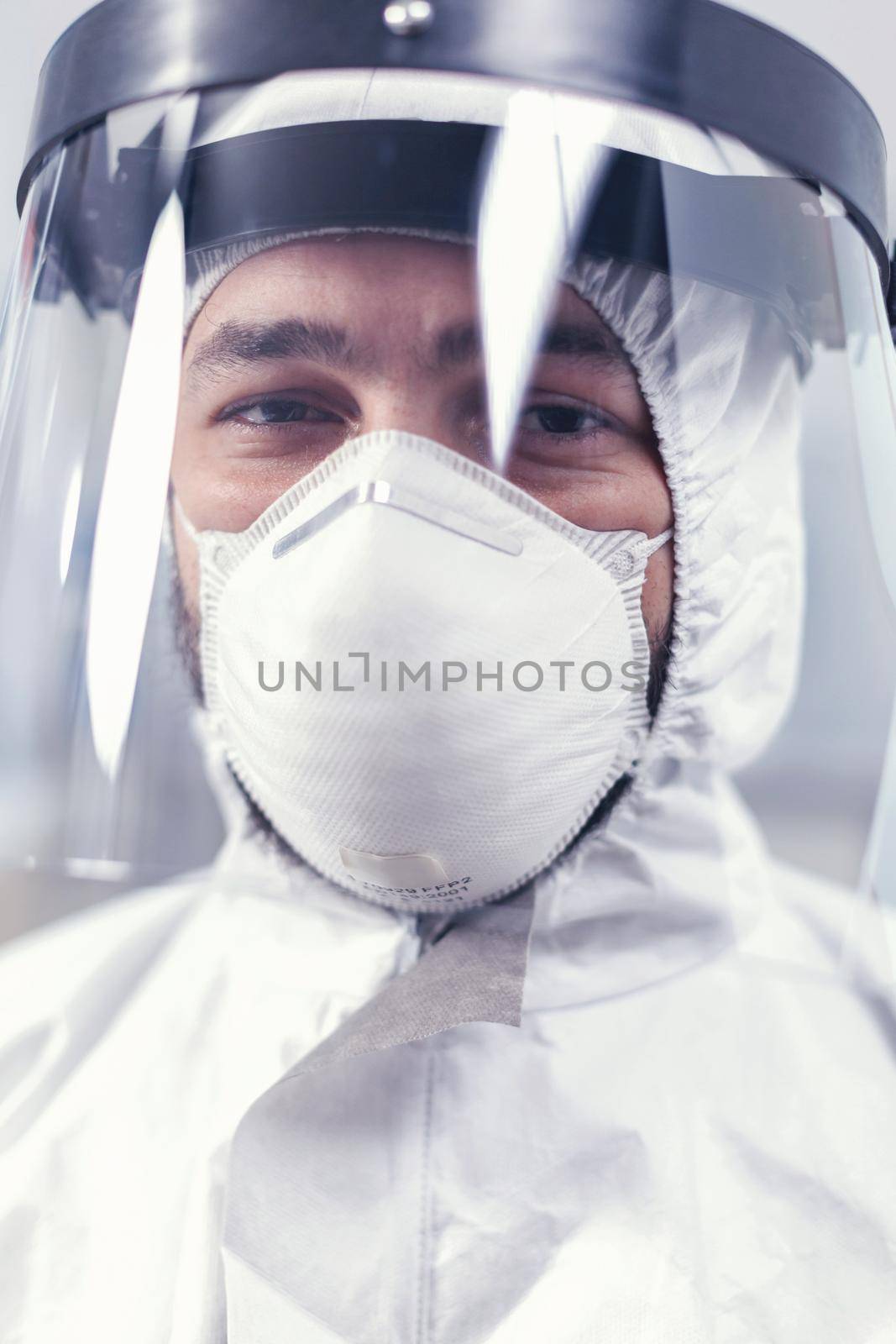 Sad medical technician wearing ppe uniform with face shield Overworked researcher dressed in protective suit against invection with coronavirus during global epidemic.
