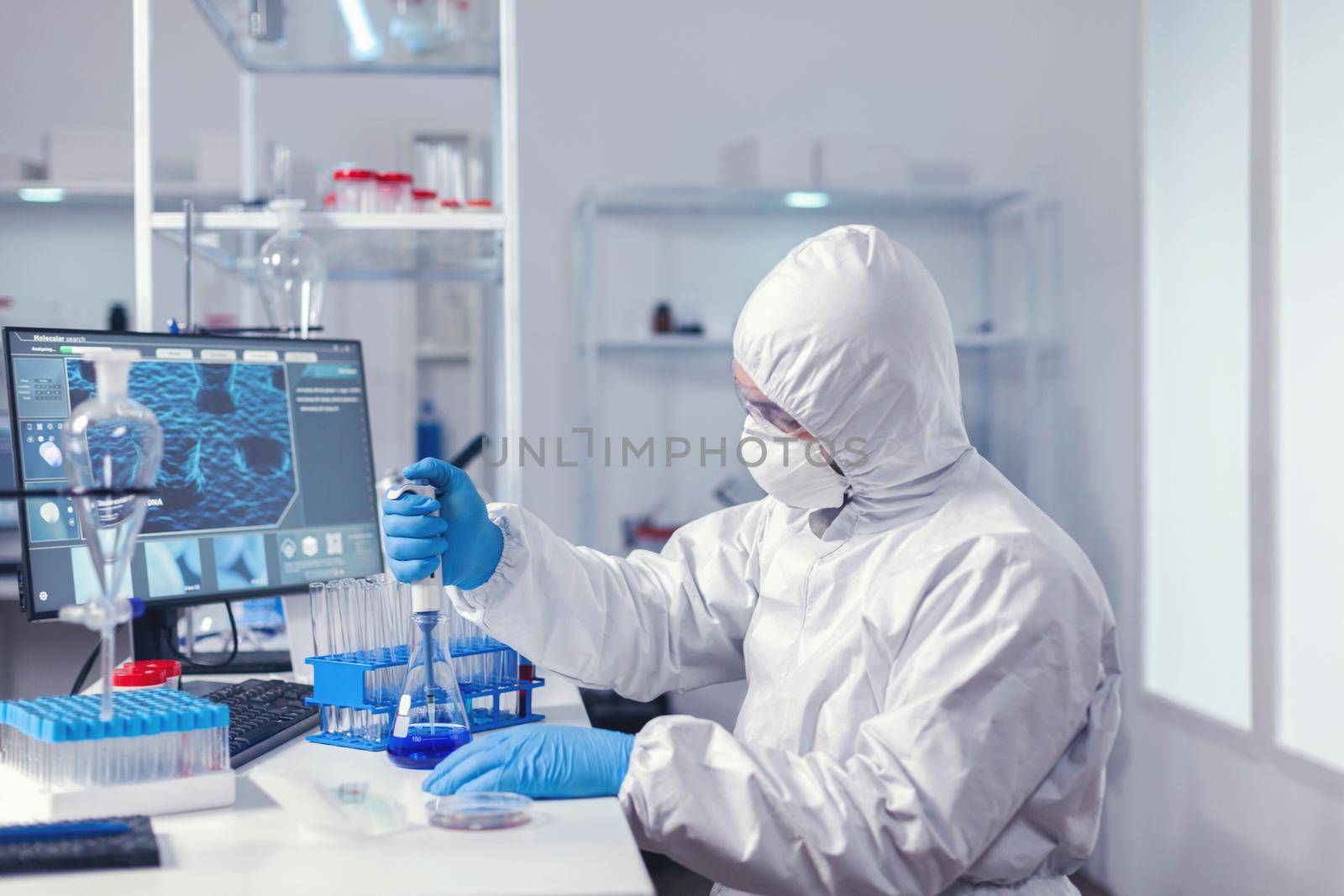 Carefull doctor working with automatic pipette taking sample from test tube. Chemist in modern laboratory doing research using dispenser during global epidemic with covid-19.