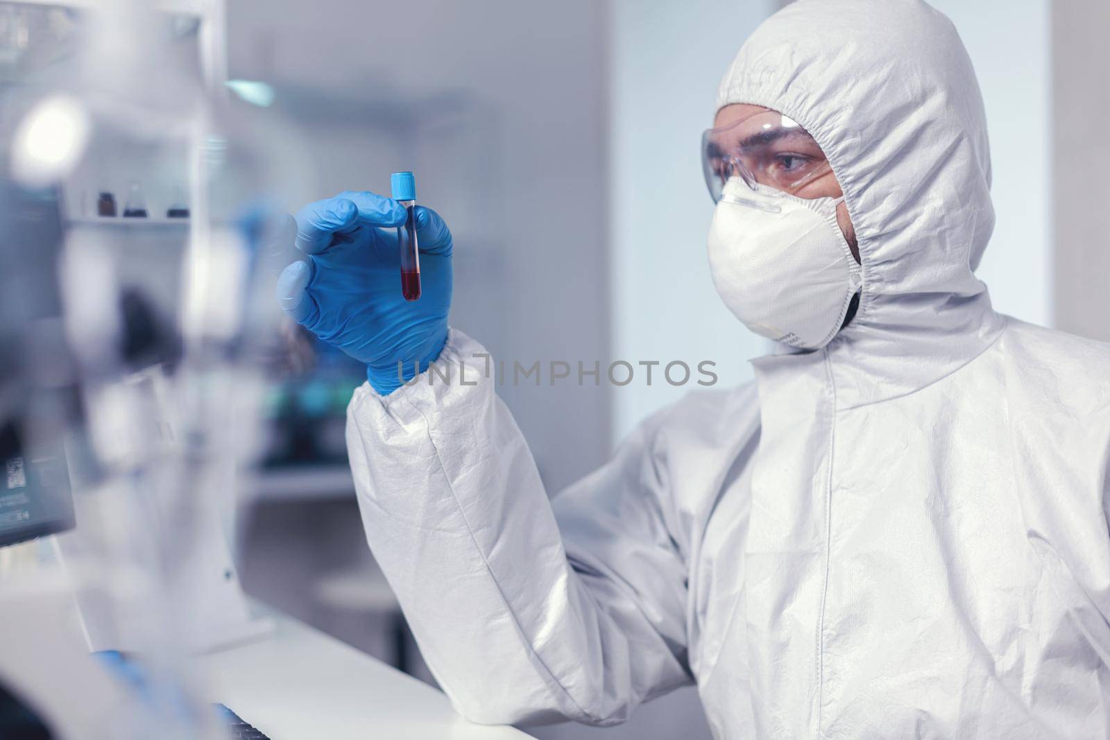 Epidemiologist analysing blood in test tube infected with coronavirus by DCStudio
