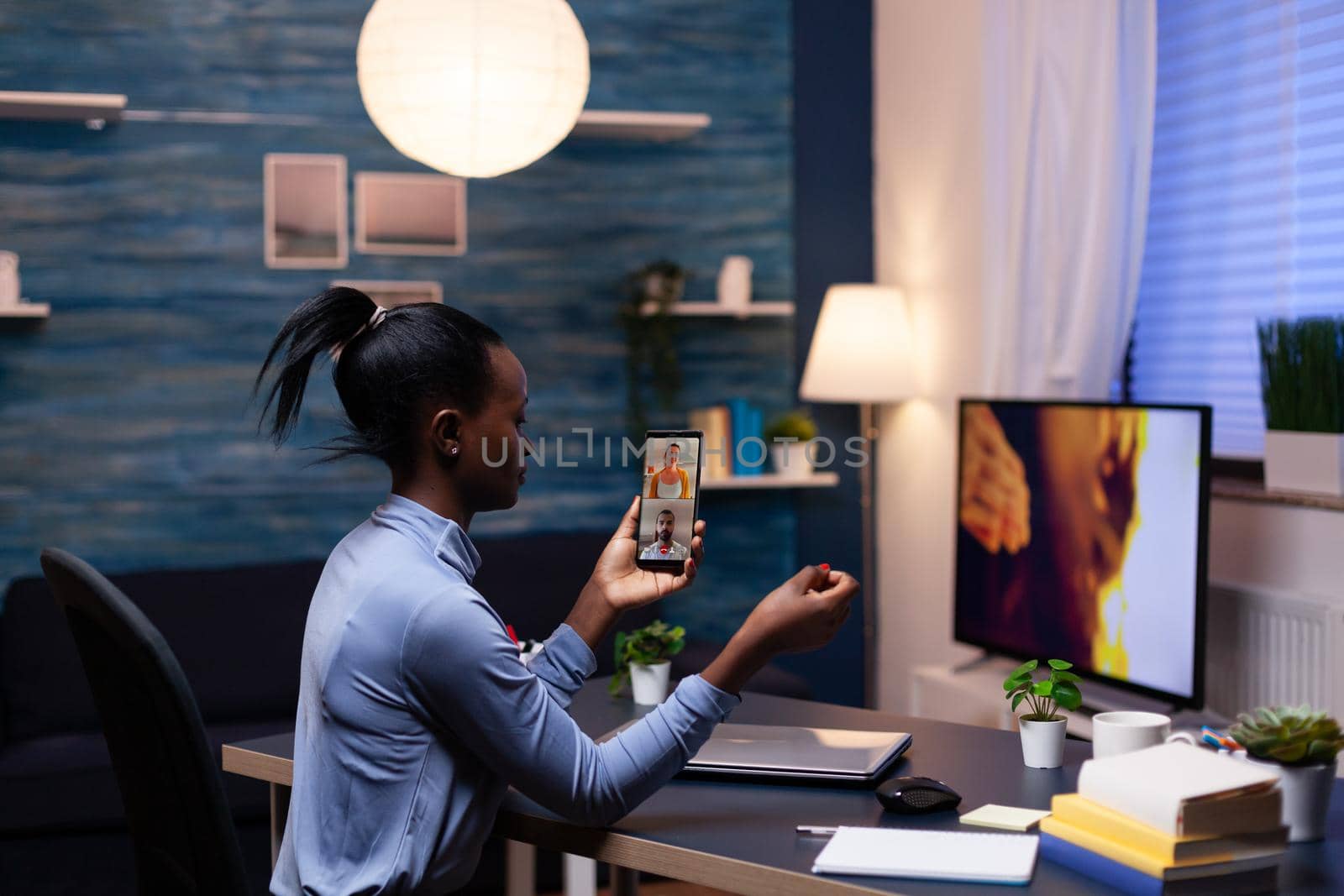 Woman with dark skin holding phone by DCStudio