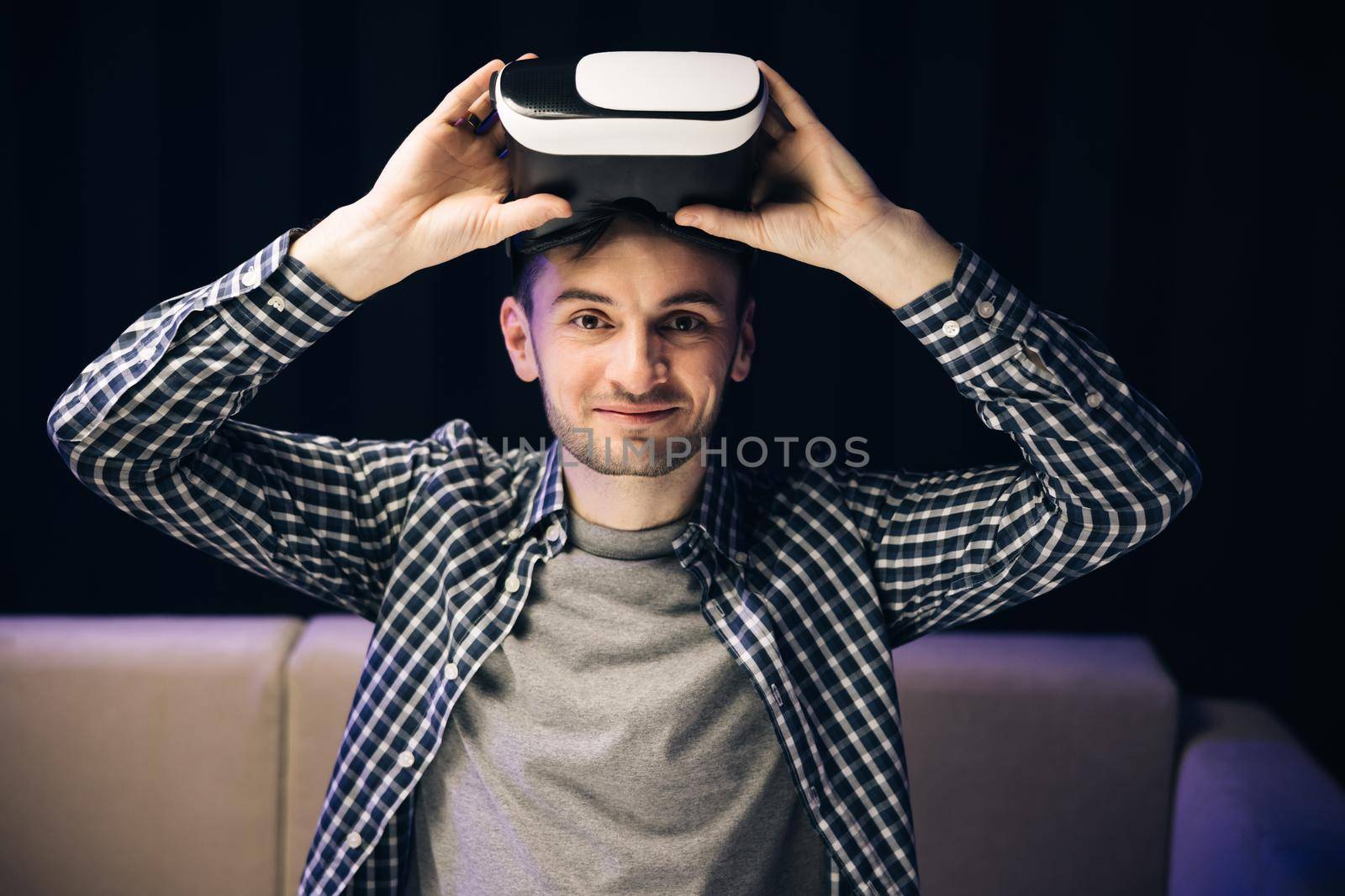 Young man using VR headset for watching the 360 video while sitting on sofa at home . Close up man using modern 3D vr glasses. Augmented Reality.
