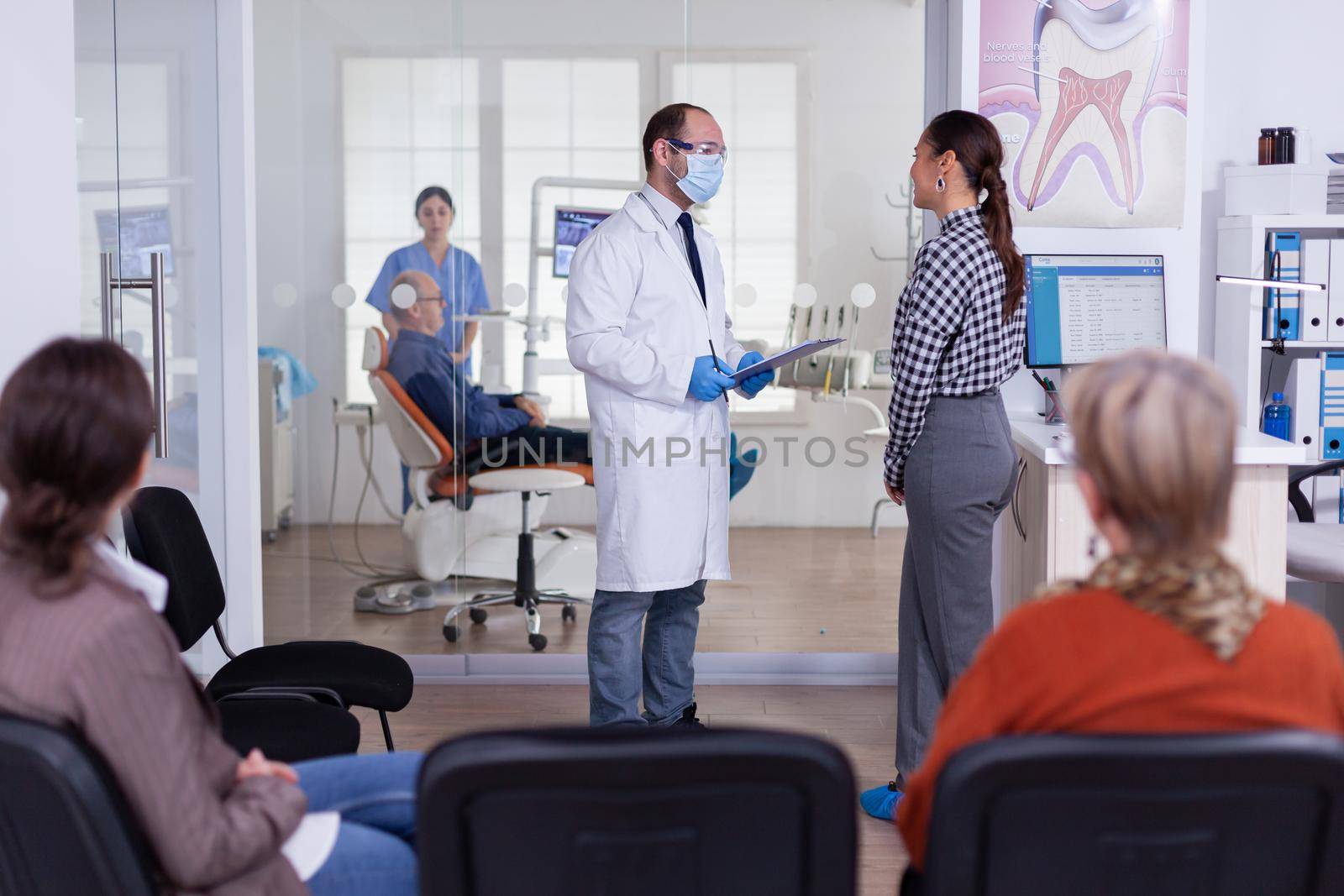 Dentist doctor interrogating woman and taking notes on clipboard by DCStudio