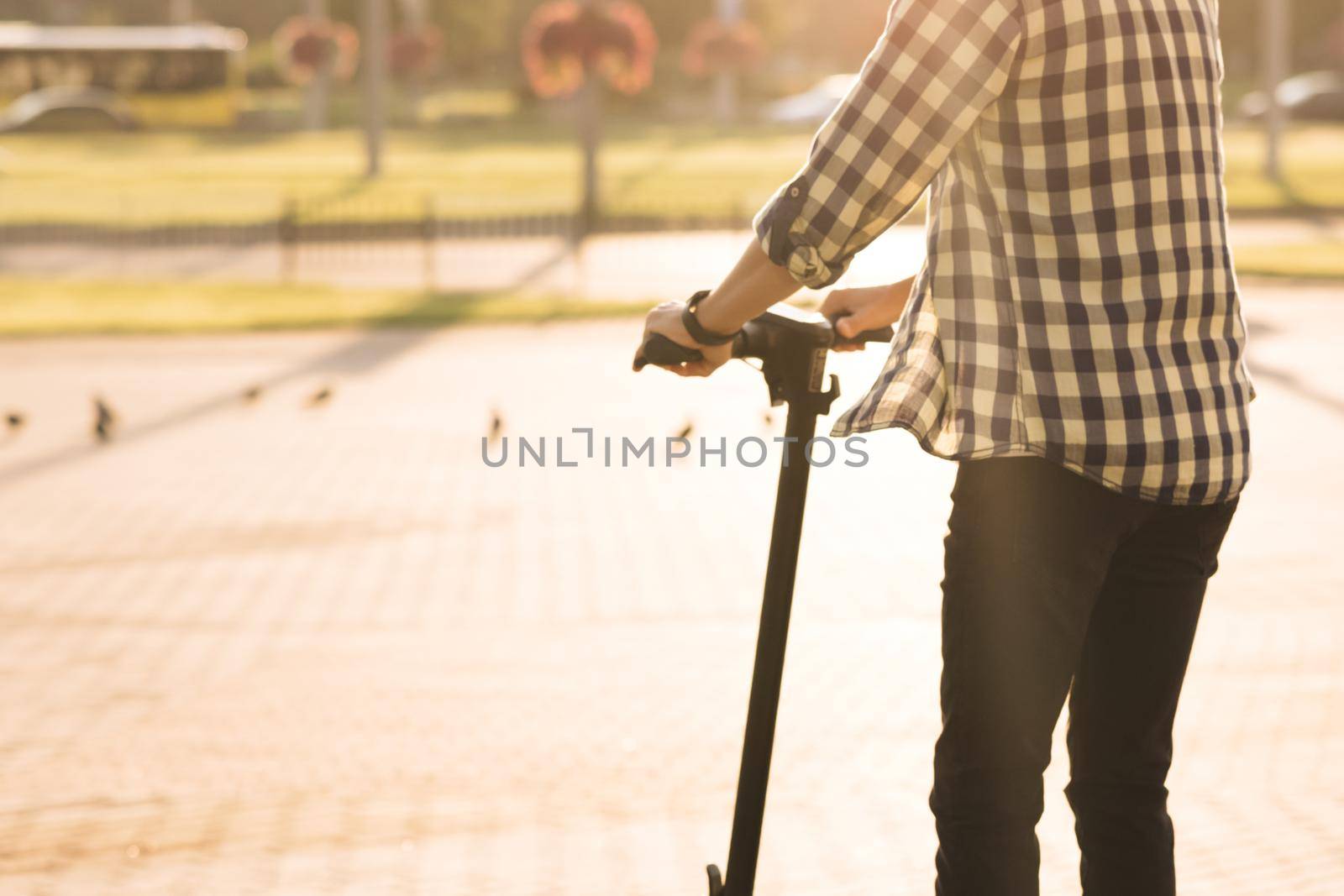Young hipster man business guy riding on fast electric scooter having fun on road in open landscape in the morning light. Ecology and urban lifestyle. Eco-friendly electric transportation by uflypro