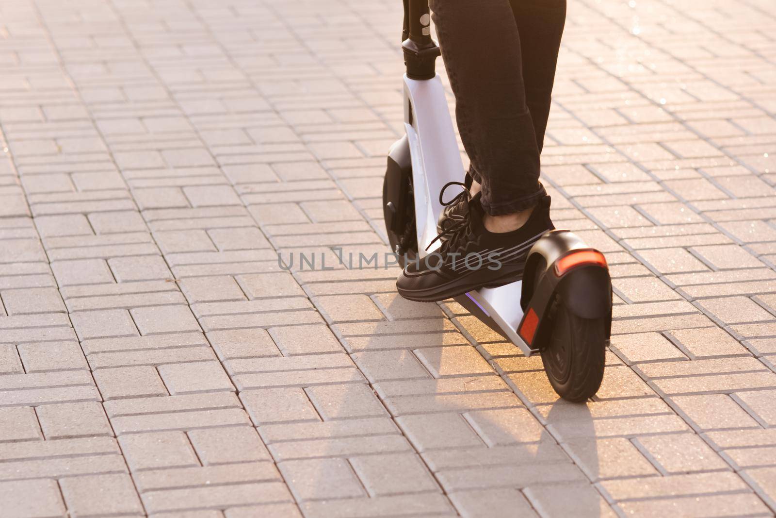 Legs man in black sneakers ride on electric mobile scooter. Modern Man Using Electric Scooter in Sunny Day. Adult man riding electric scooter to work. Eco friendly transportation by uflypro