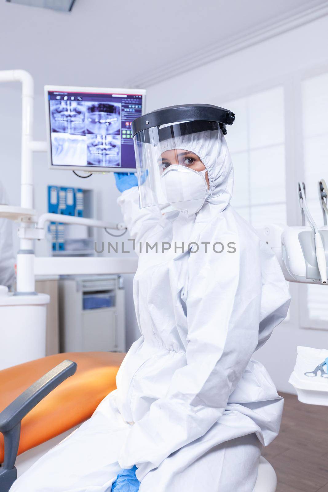 Pov of patient listening dentist talking about teeth hygine ponting at digital x-ray. Stomatology specialist wearing protective suit against infection with coronavirus pointing at radiography.