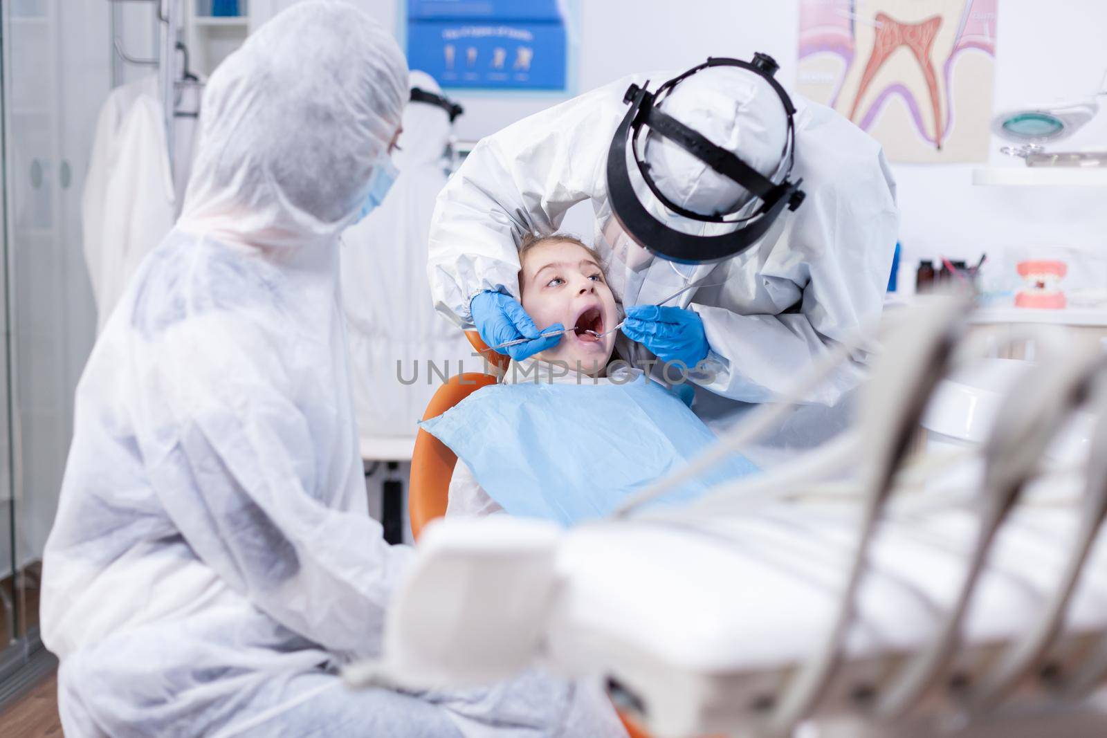 Little girl with mouth open getting caries treatment by DCStudio