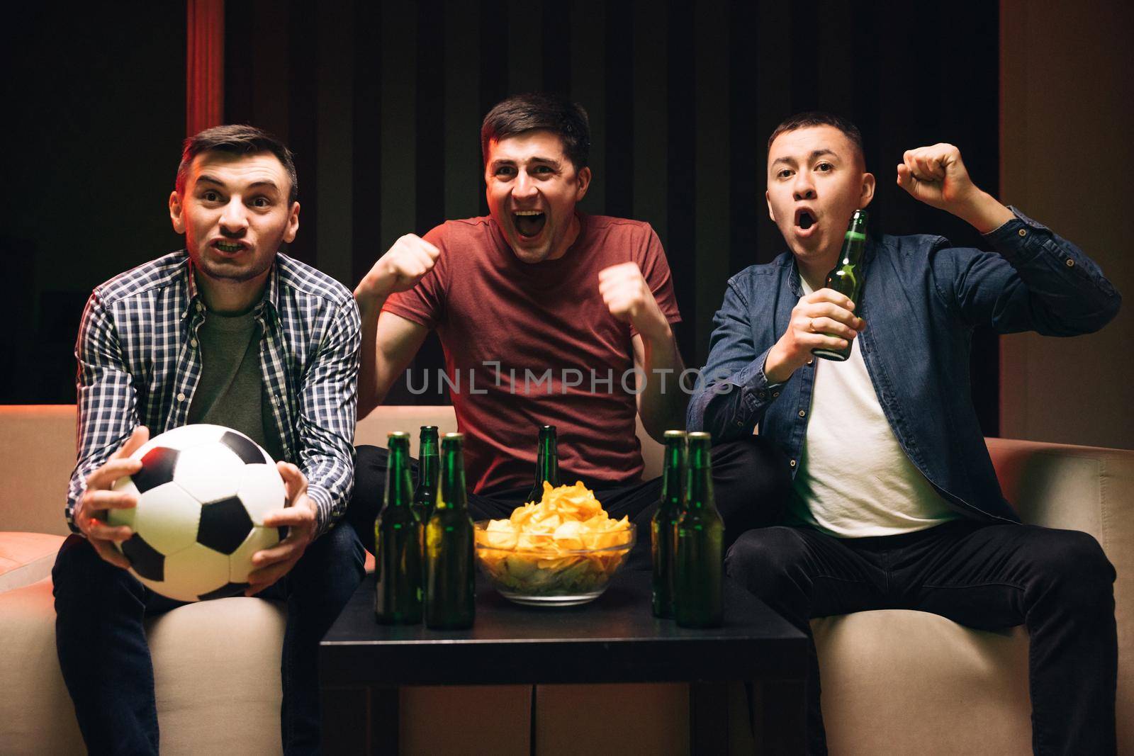 Young male sport fans shout watching football game together at home. Expressing, screaming and emotion. Loyal football fans supporting their team by uflypro