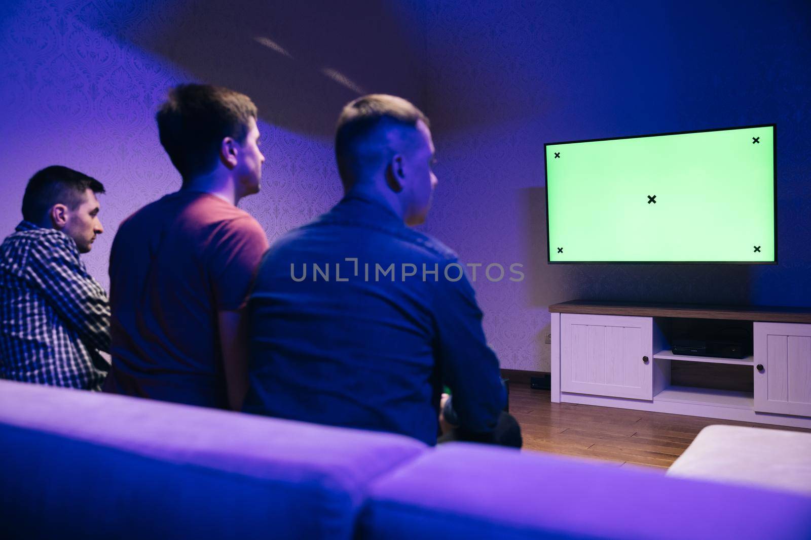 Back Shot of a Gamers Playing and Winning in Online Video Game on His console with Green Chroma Key Screen Personal TV. Cozy Evening at Home.