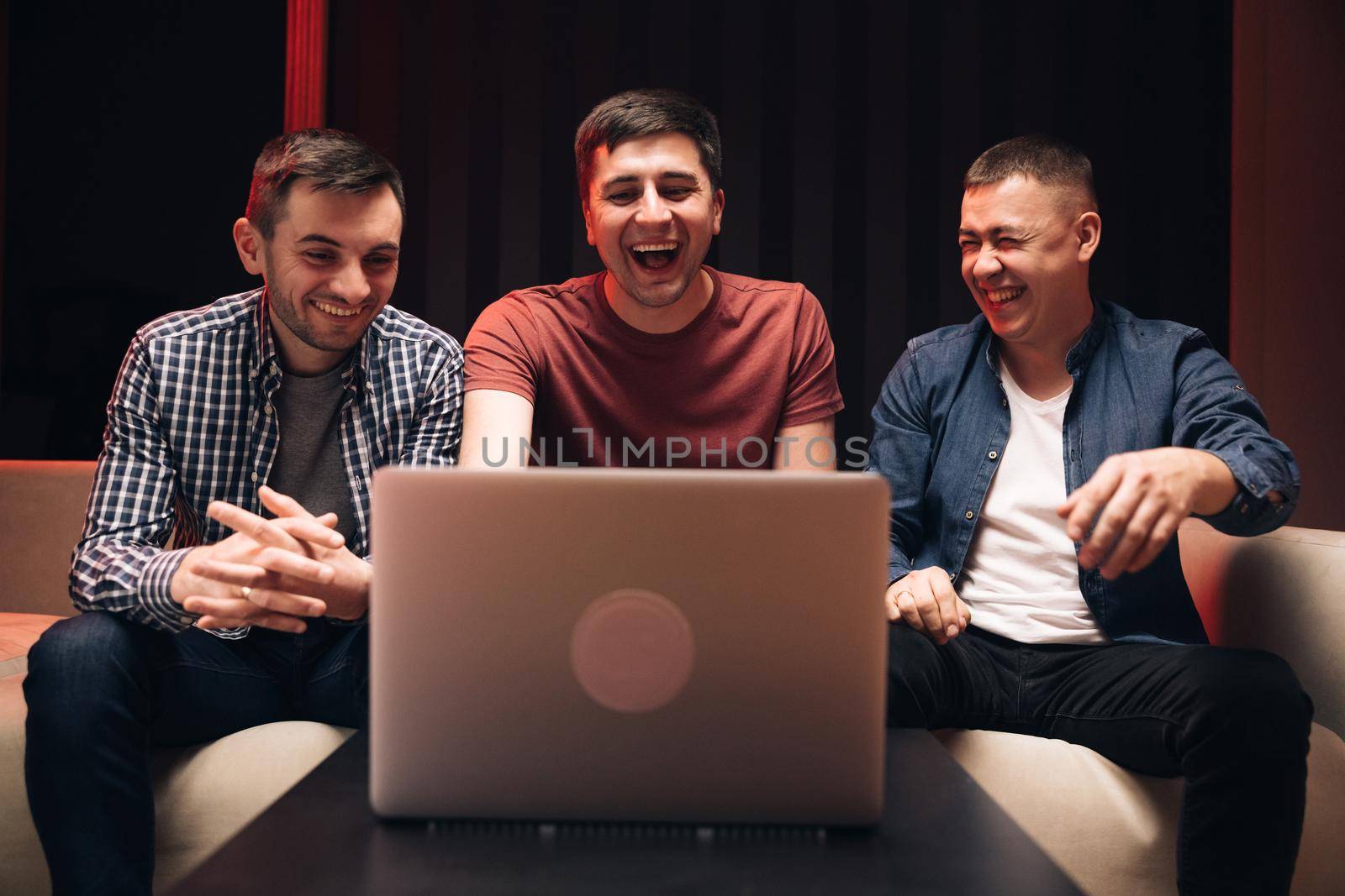 Men fans buddies supporters cheering celebrating victory goal score support winning team. Male friends watching online football game match at laptop. Men watching football in streaming on laptop by uflypro