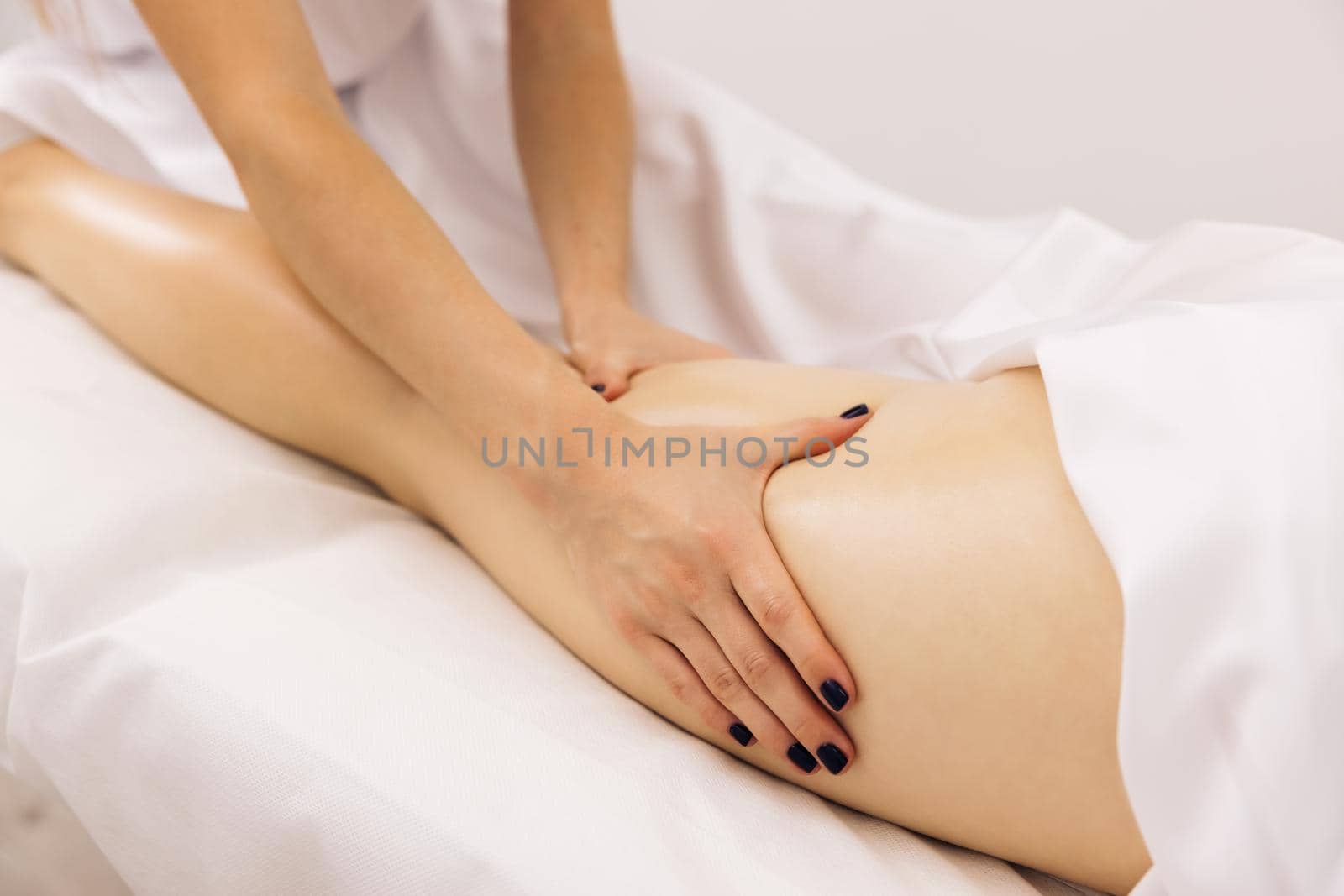 Masseur is doing massage of back of woman lying in beauty salon. Professional is massaging and touching skin of female client, using traditional techniques. Specialist works with body of patient