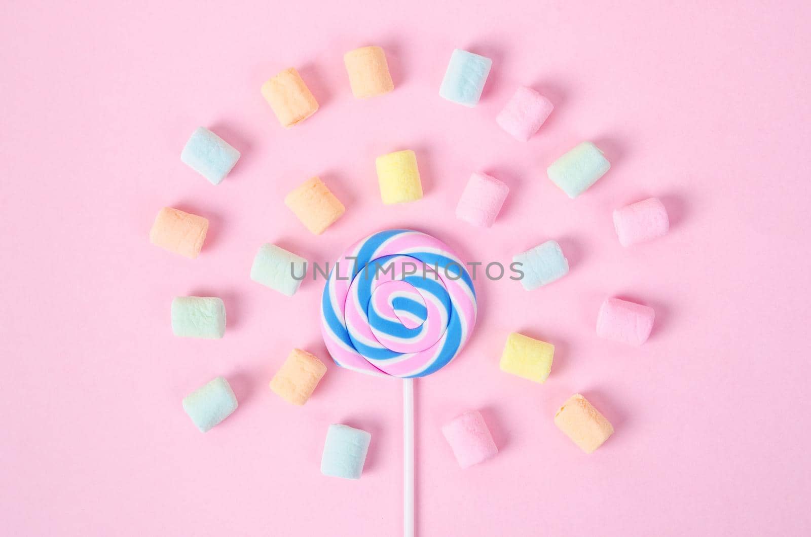 Colorful marshmallows and sweet candy on pink background.