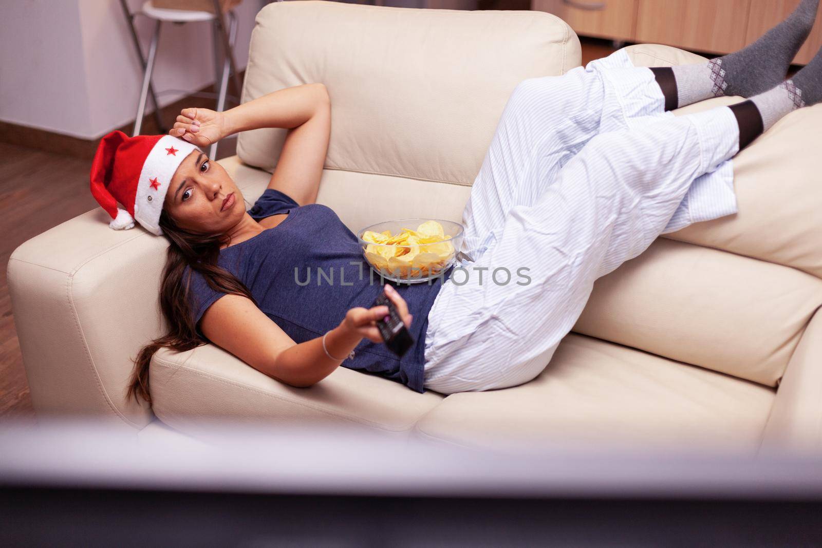 Adult person relaxing on couch changing channel using remote searching xmas fuuny movie by DCStudio