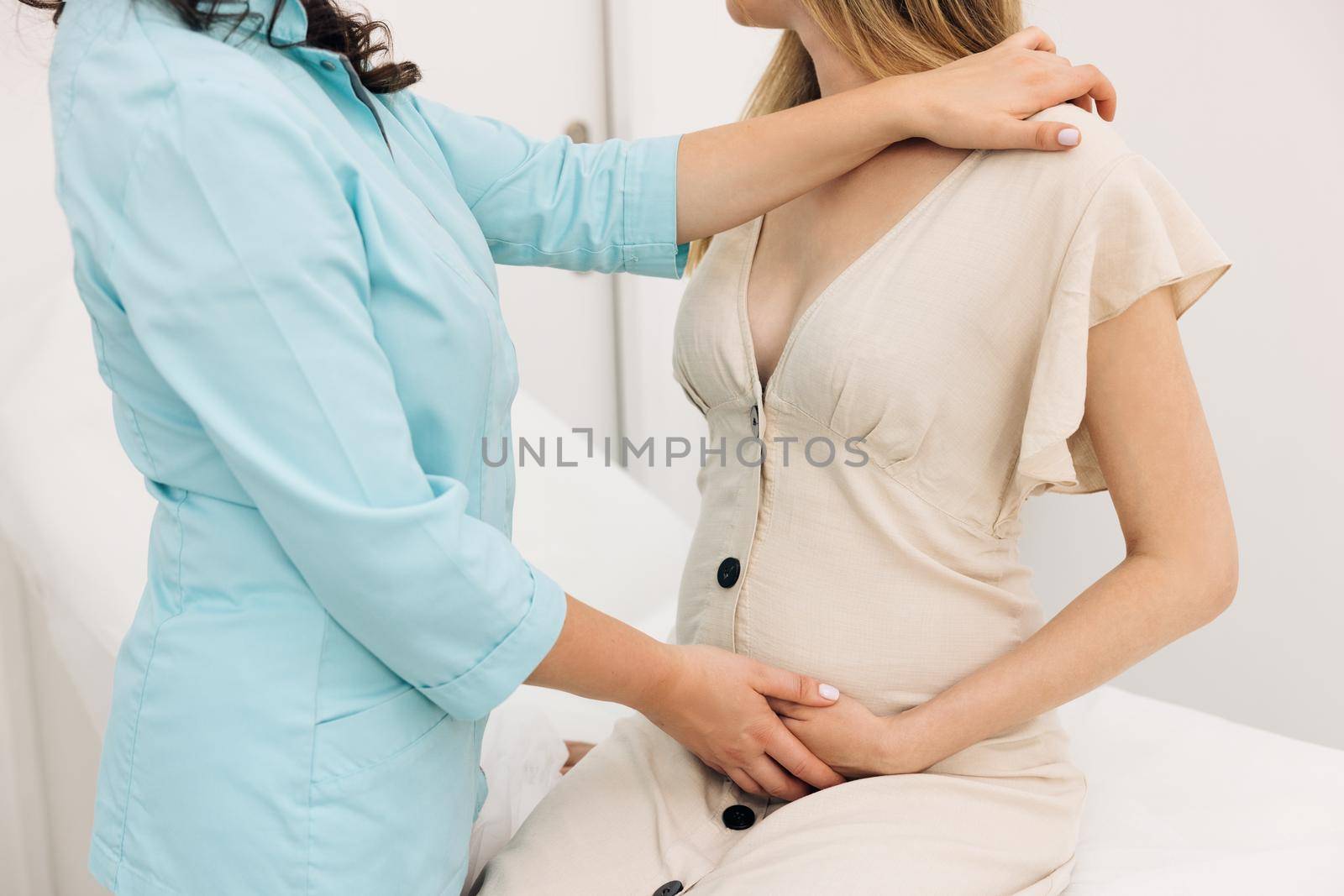 Pregnancy and maternity healthcare concept. Physiotherapist woman massaging tummy on pregnant woman on a stretcher. Pregnant woman visit gynecologist doctor at hospital or medical clinic