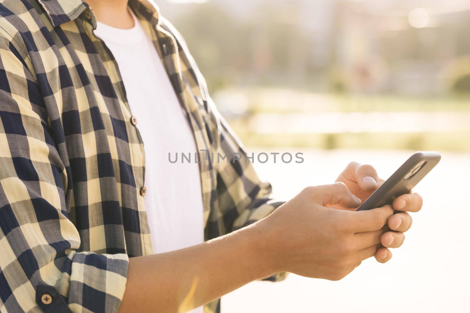 Man with cell phone on city street people and cars background, crossroad use application. Close up of man using touch mobile phone outdoor.