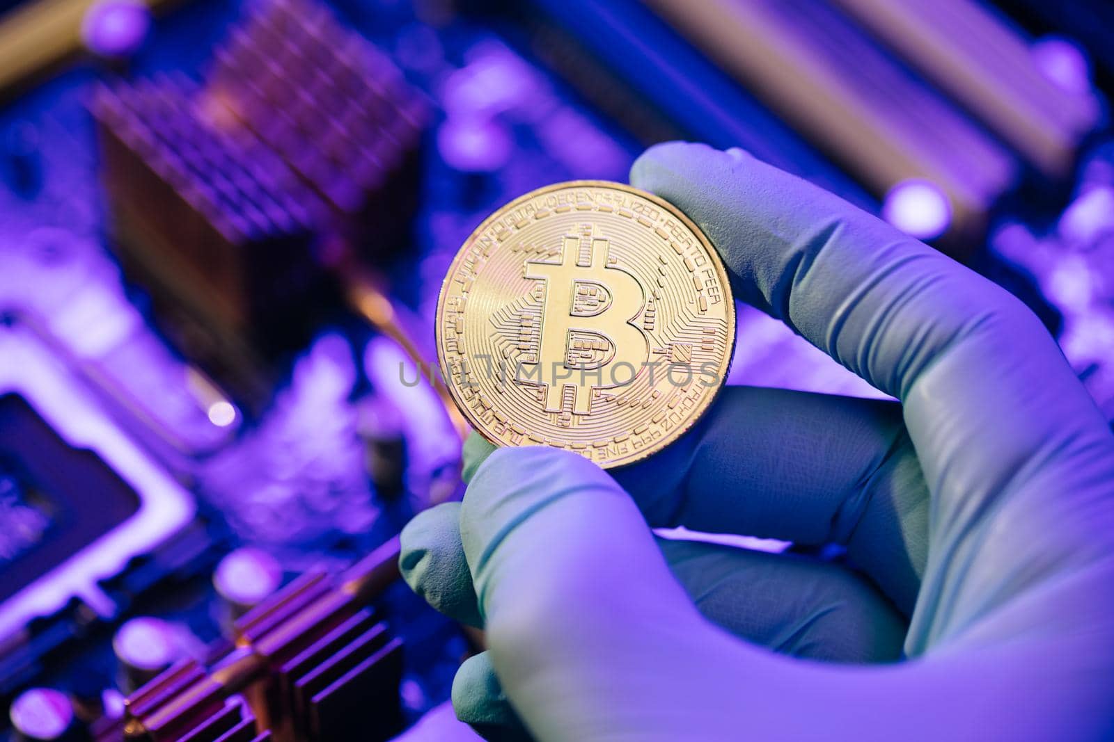 Businessman hands in gloves hold gold Bitcoin on motherboard background. Cryptocurrency in the fingers. Person shows future currency. Mining, trading by uflypro