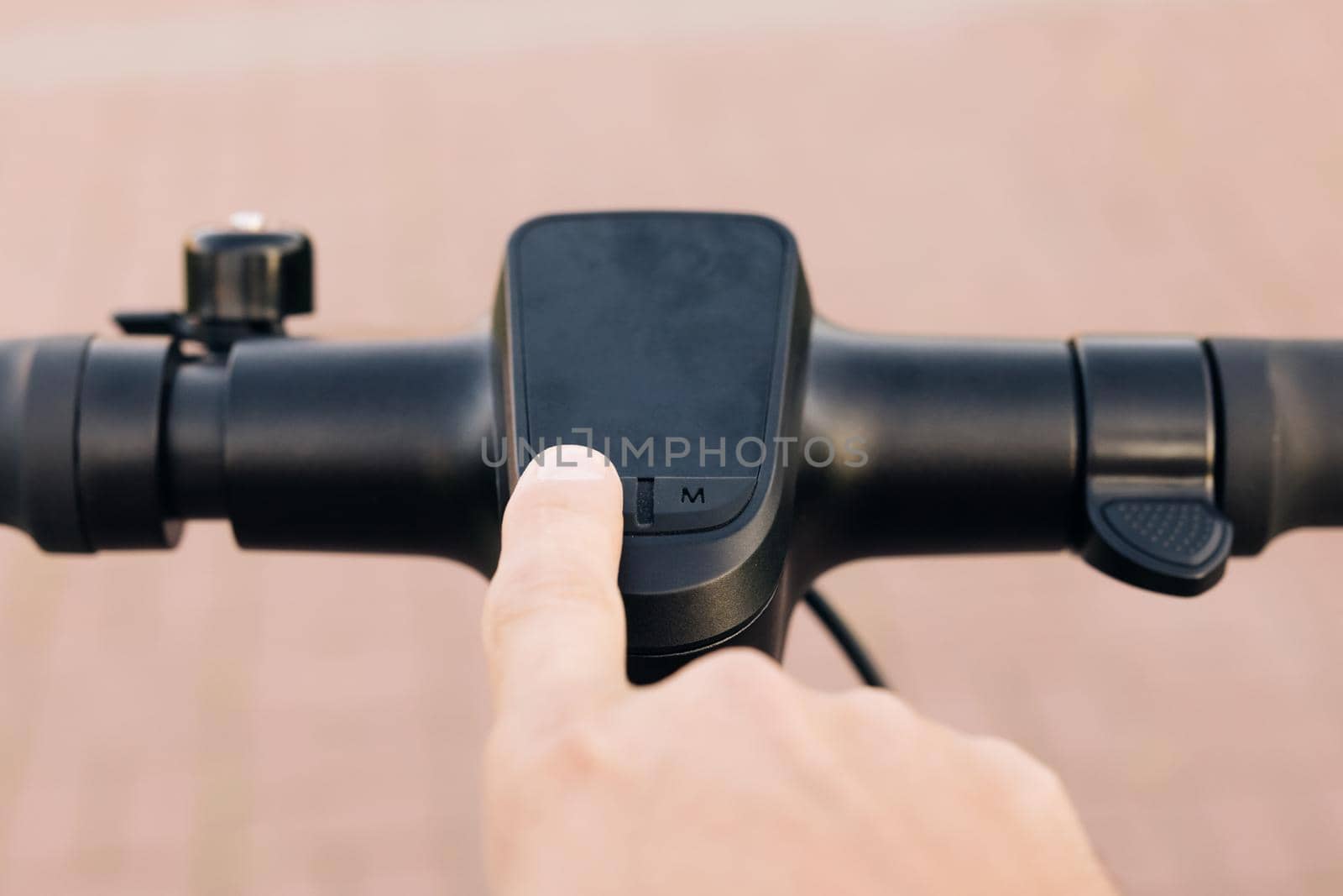 Close up of hipster man turns on the electric scooter. Male is pushing start button of modern gadget and driving along street of city. Hands of a young man close-up. Ecological alternative transport.