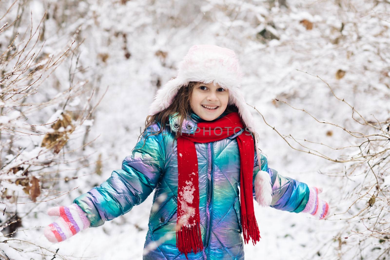 Happy child girl plays with a snow in winter day. Girl enjoys winter, frosty day. Playing with snow on winter holidays. Walk in winter forest by uflypro