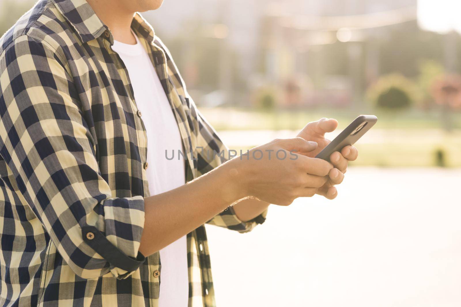 Close up of man using touch mobile phone outdoor. Student man with cell phone on city street people and cars background, crossroad use application by uflypro
