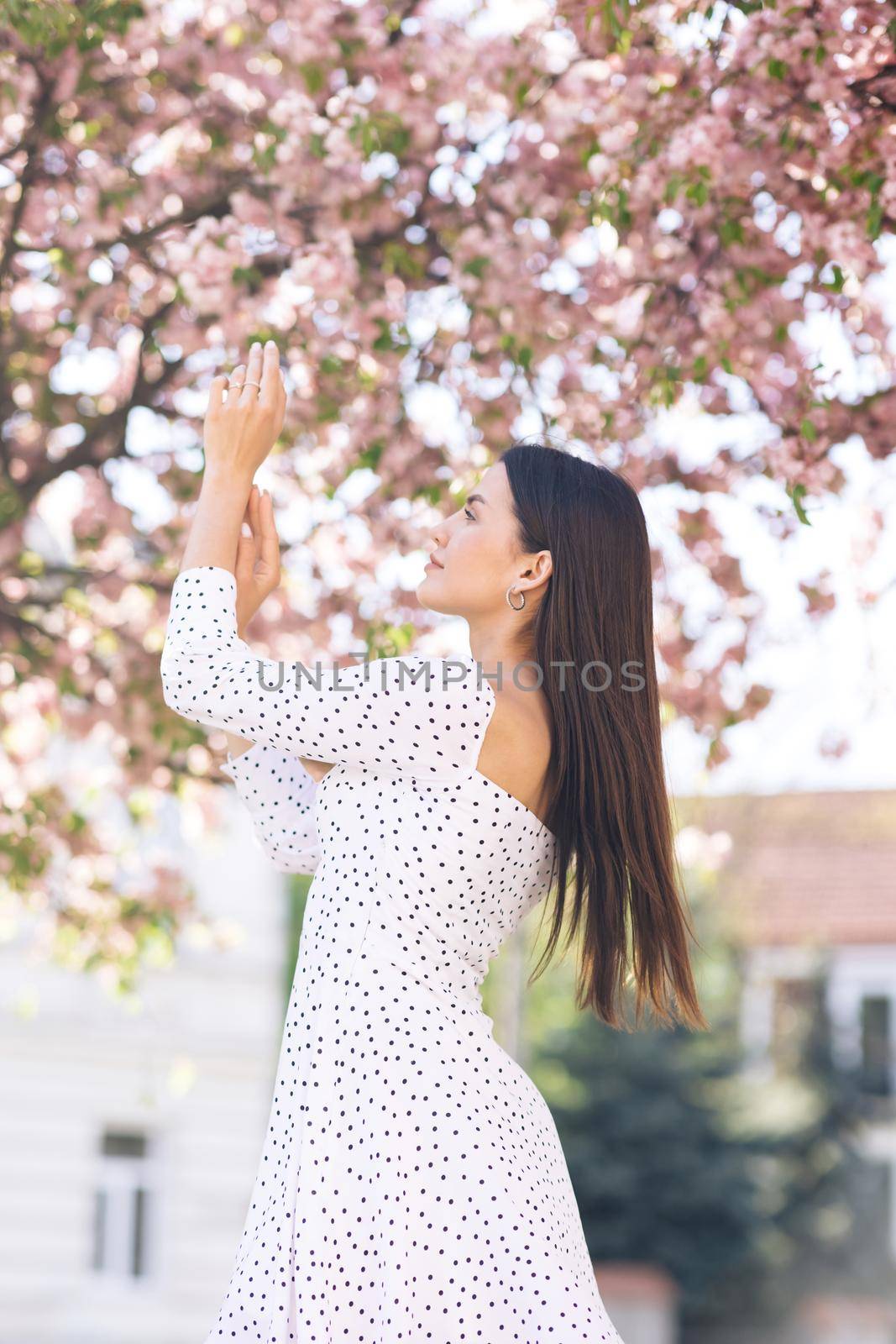Girl with pink cherry blossom petals in cherry blossom forest