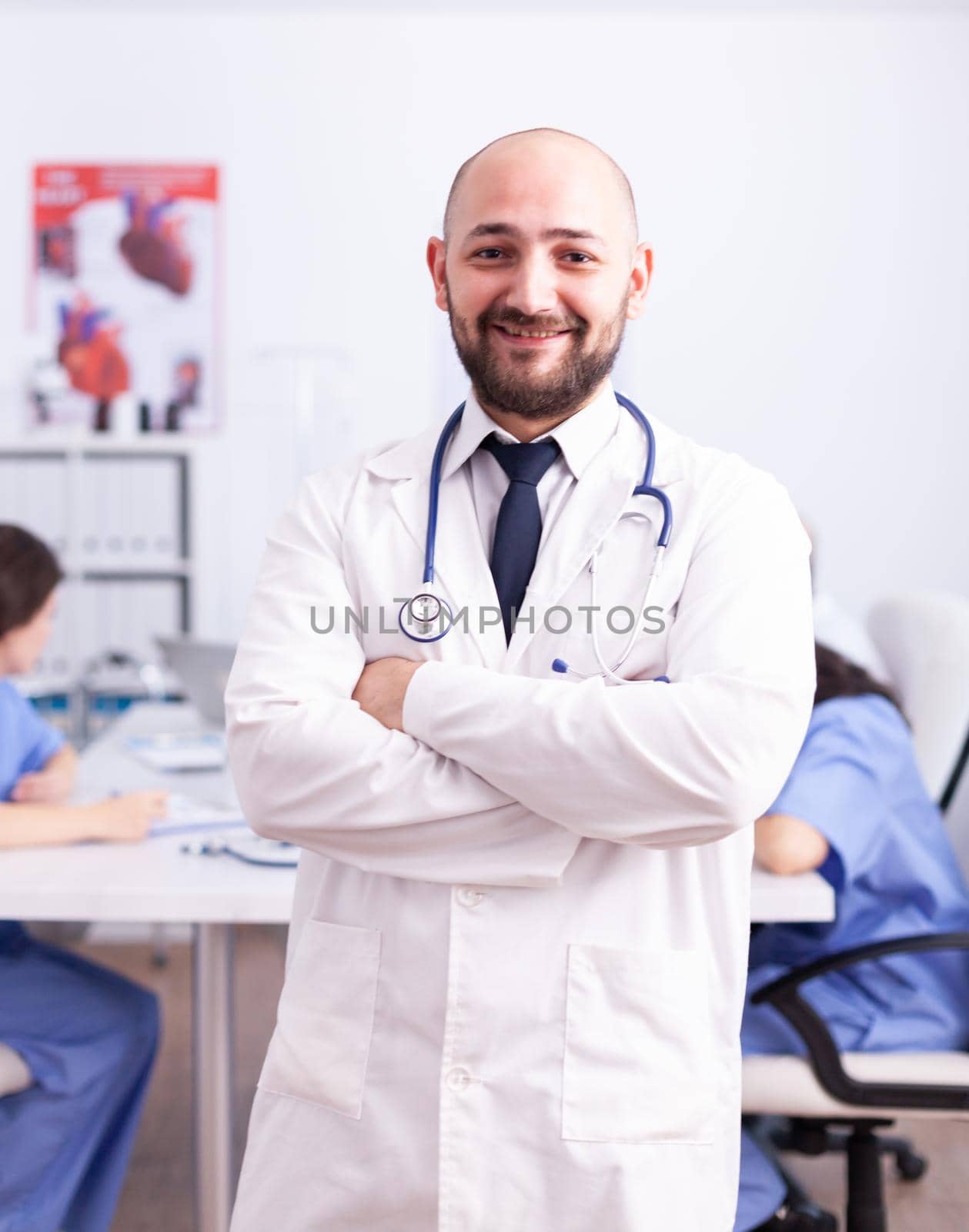 Portrait of young expert doctor looking at camera in hospital conference room. Friendly medical practitioner in clinic meeting room, robe, specialist.