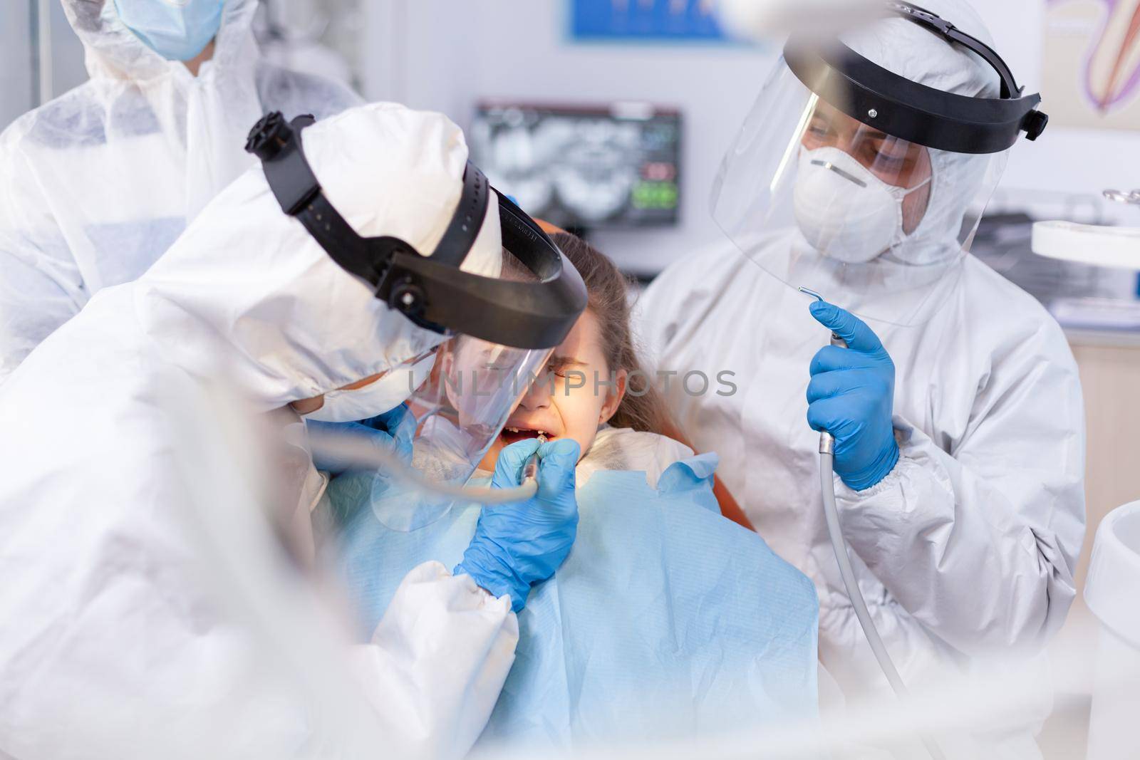 Orthodontist and assistant using drill on little girl cavity by DCStudio