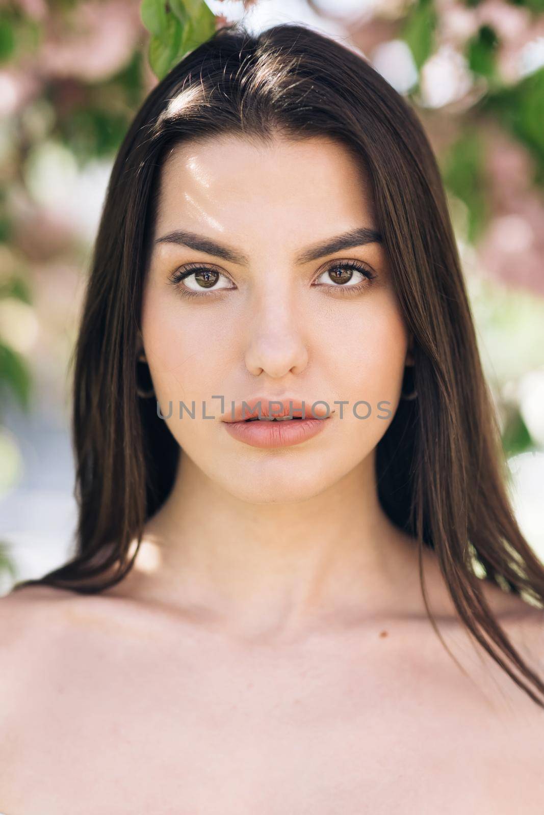 Glamour portrait of beautiful woman model with fresh daily makeup and romantic wavy hairstyle. Fashion shiny highlighter on skin, sexy gloss lips make-up and dark eyebrows.
