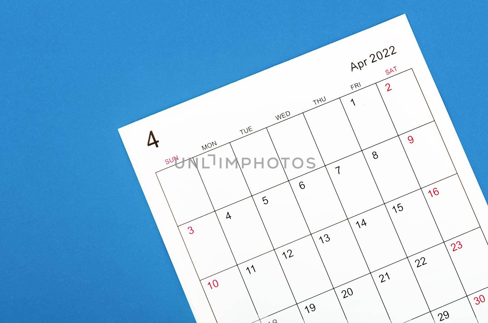Close up April 2022 calendar sheet on blue background.