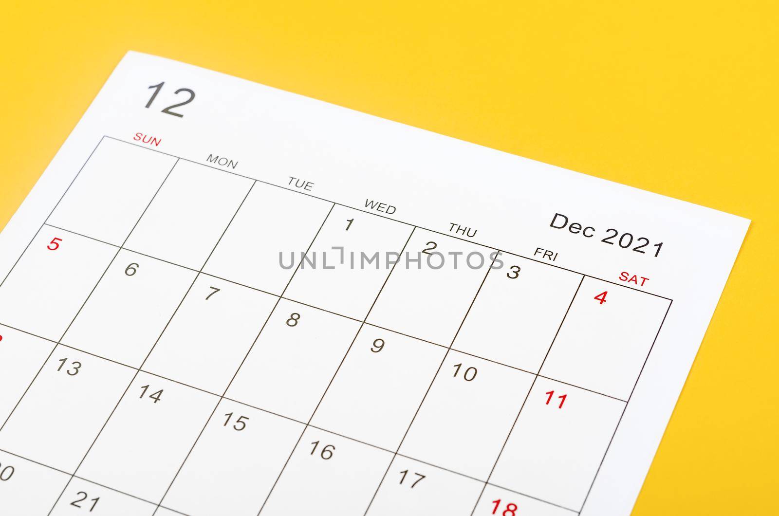 Close up December 2021 calendar sheet on yellow background.